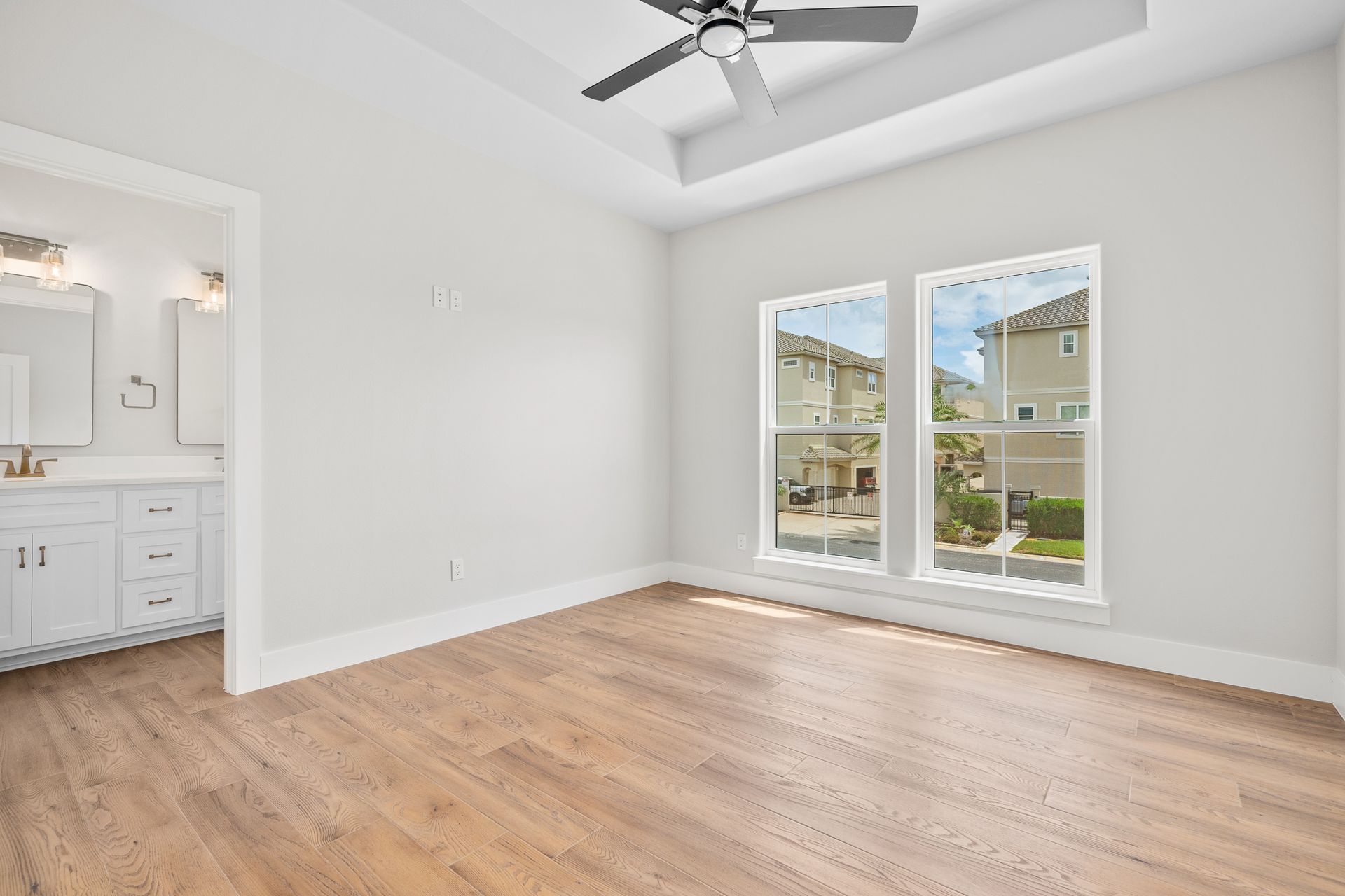 An empty bedroom with hardwood floors and a ceiling fan.