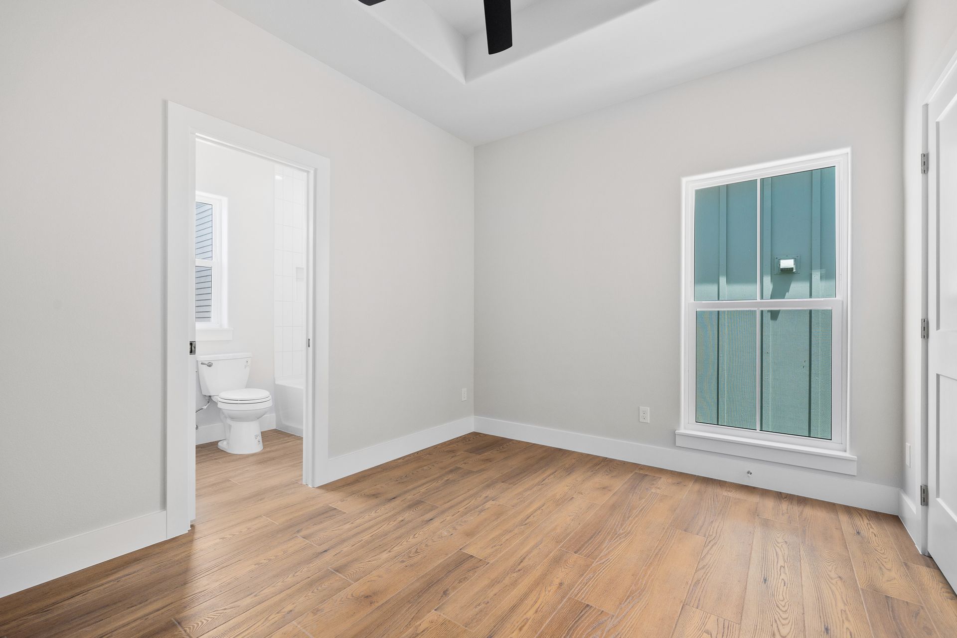 An empty bedroom with hardwood floors and a toilet.