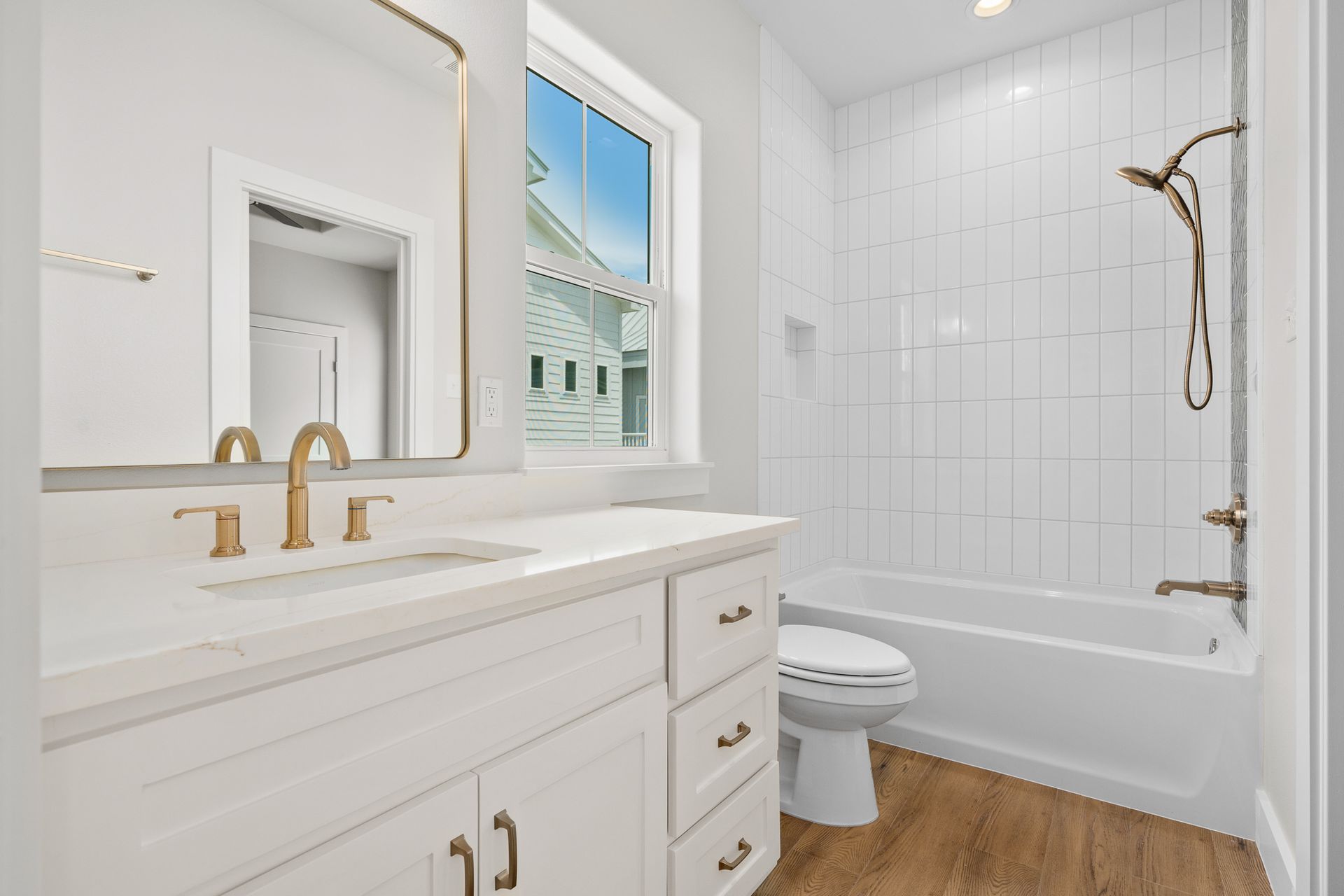 A bathroom with a sink , toilet , tub and mirror.