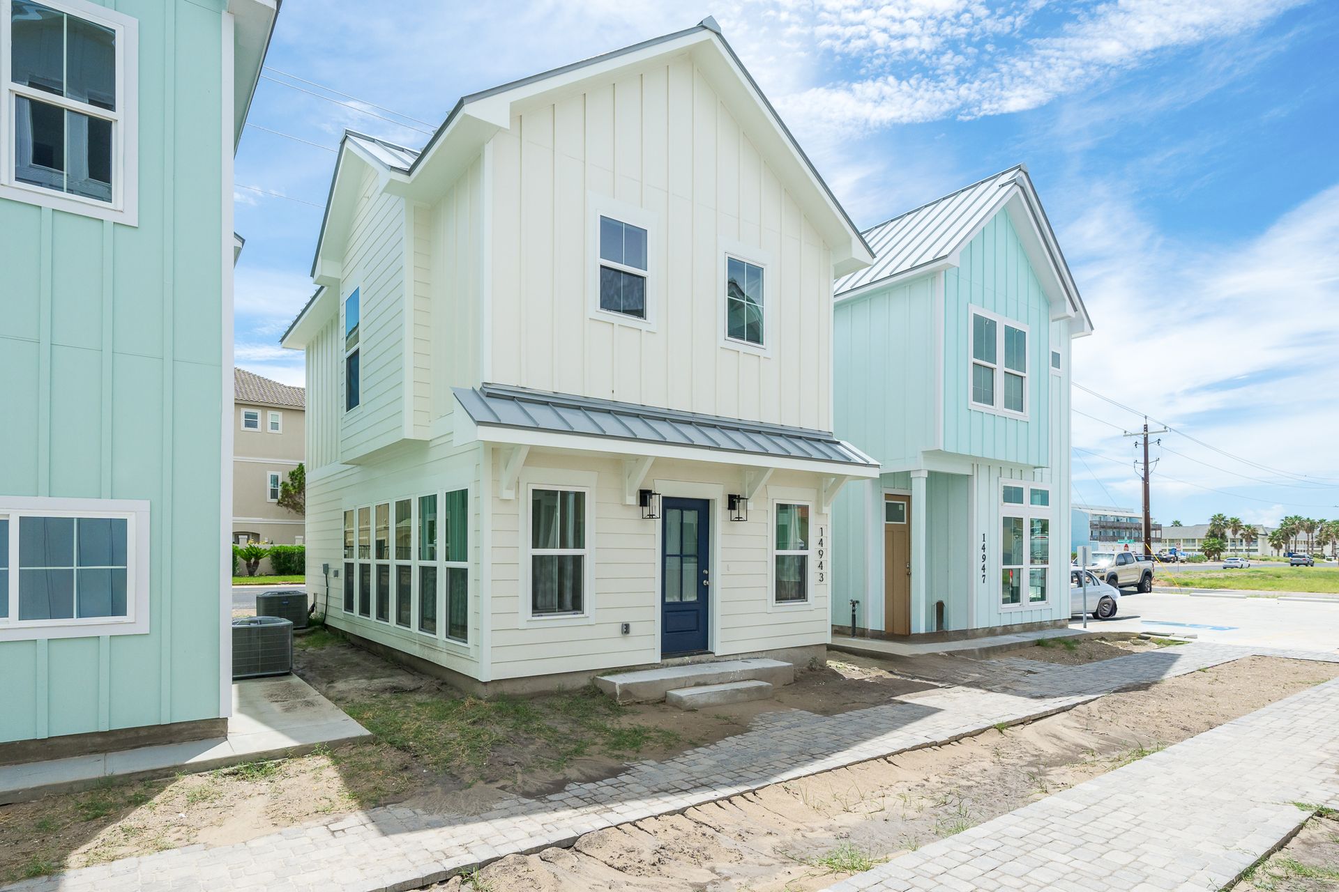 A white house with a blue door is surrounded by other houses.