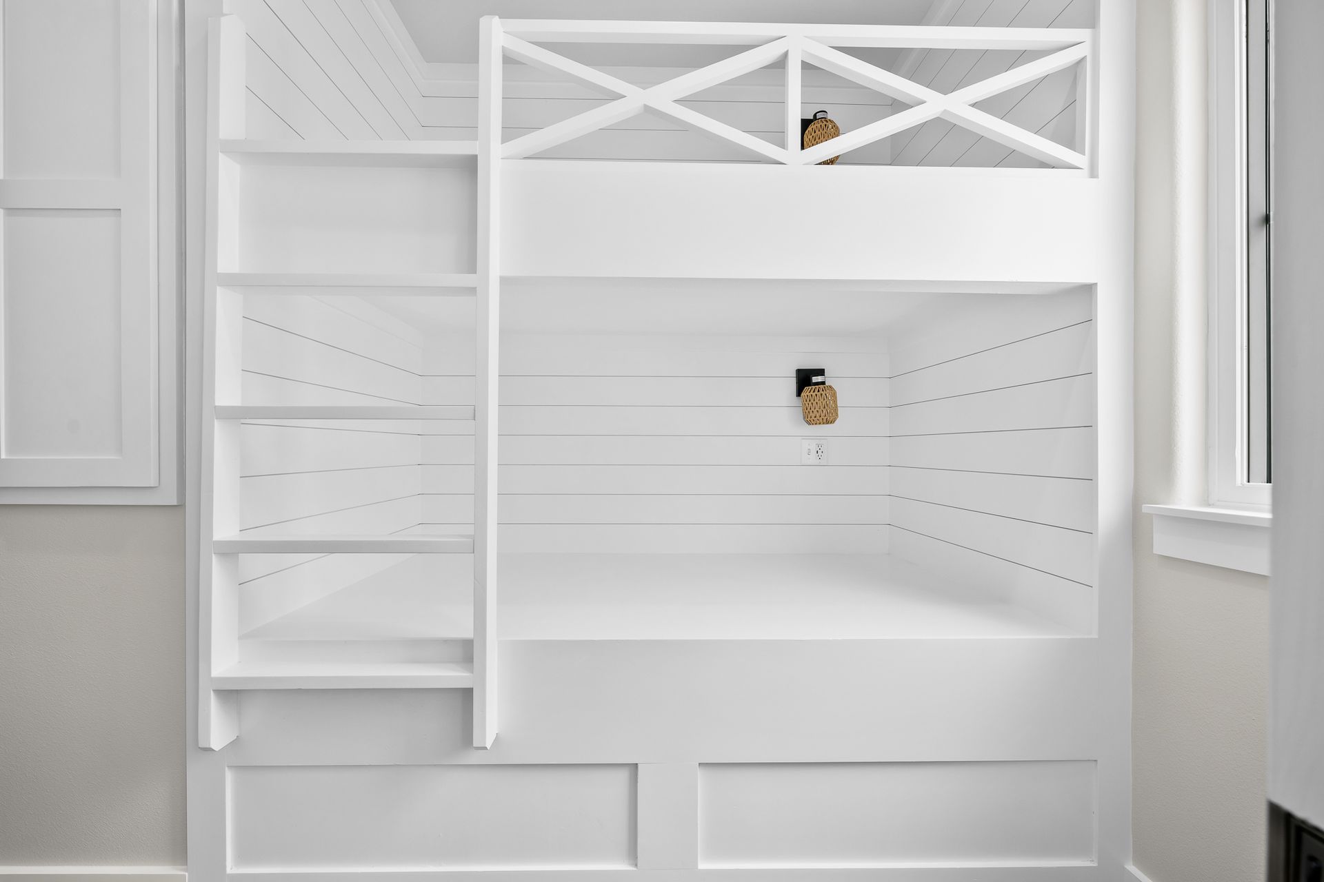 A white bunk bed with stairs and shelves in a room