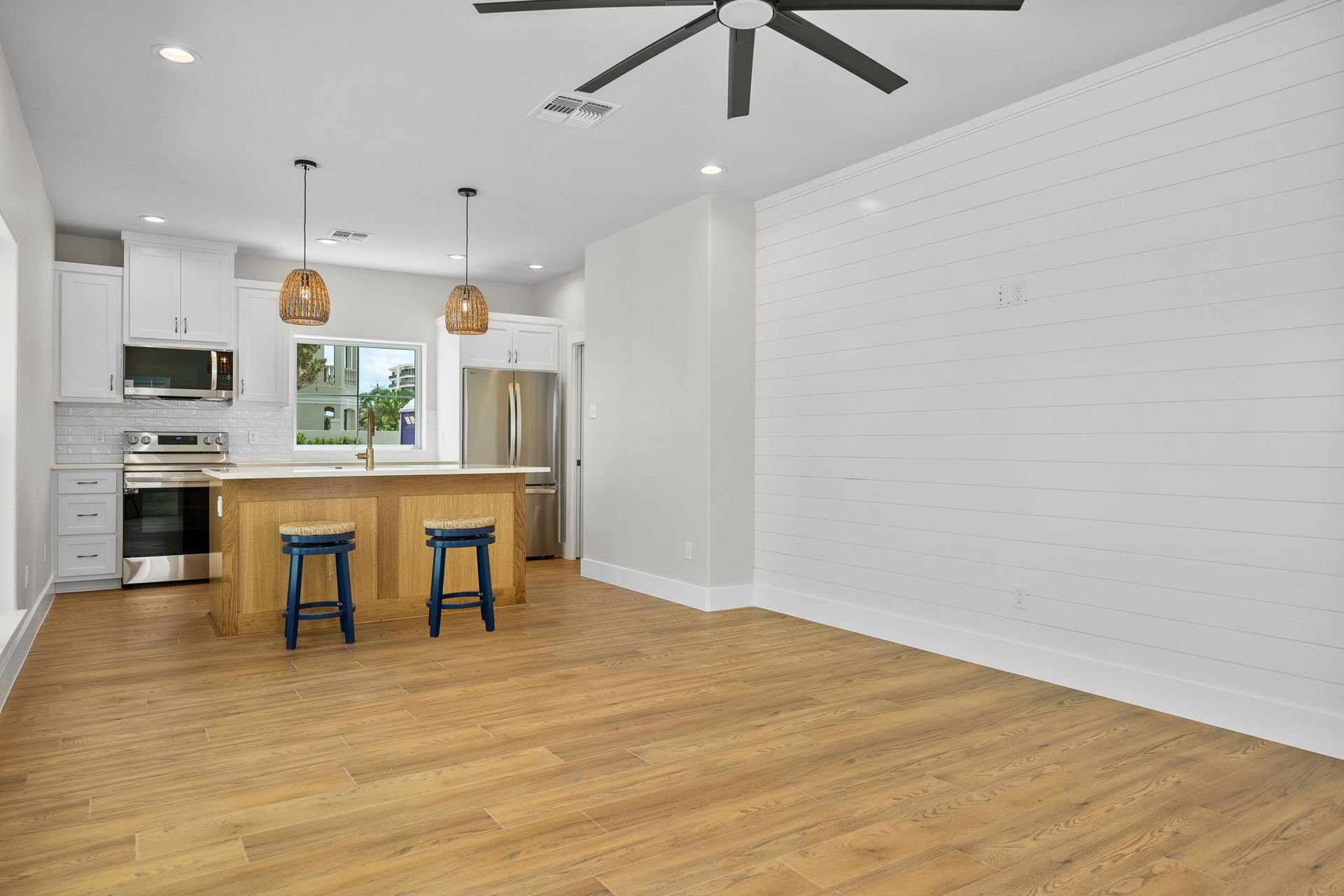 A kitchen with a ceiling fan and wooden floors.