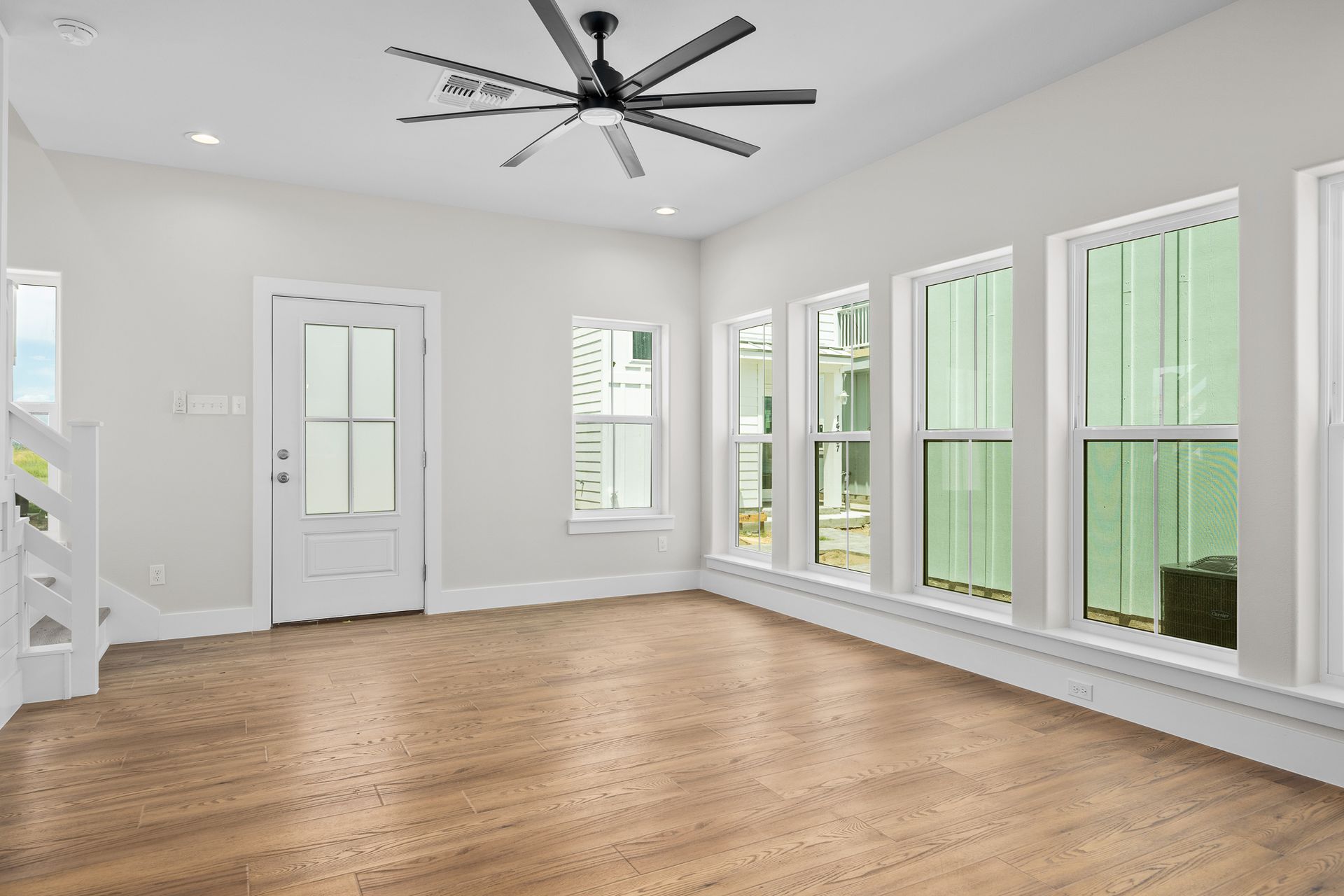 An empty living room with hardwood floors and a ceiling fan.