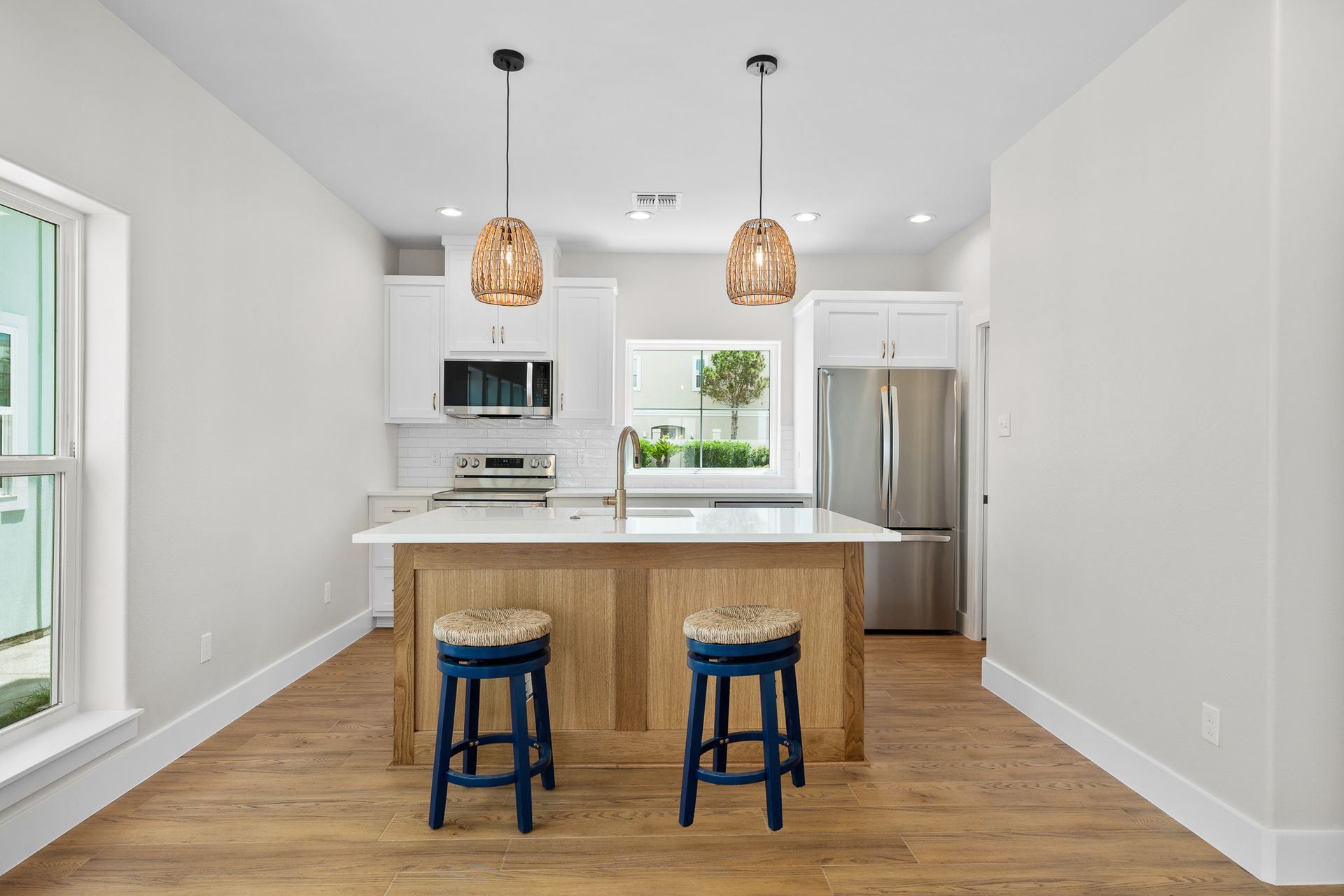 A kitchen with a large island and two blue stools.