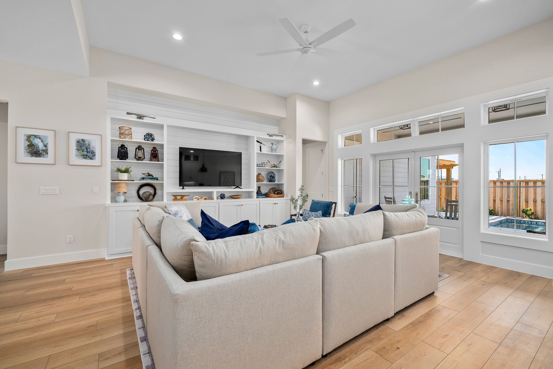 A living room with a couch , television , and ceiling fan.