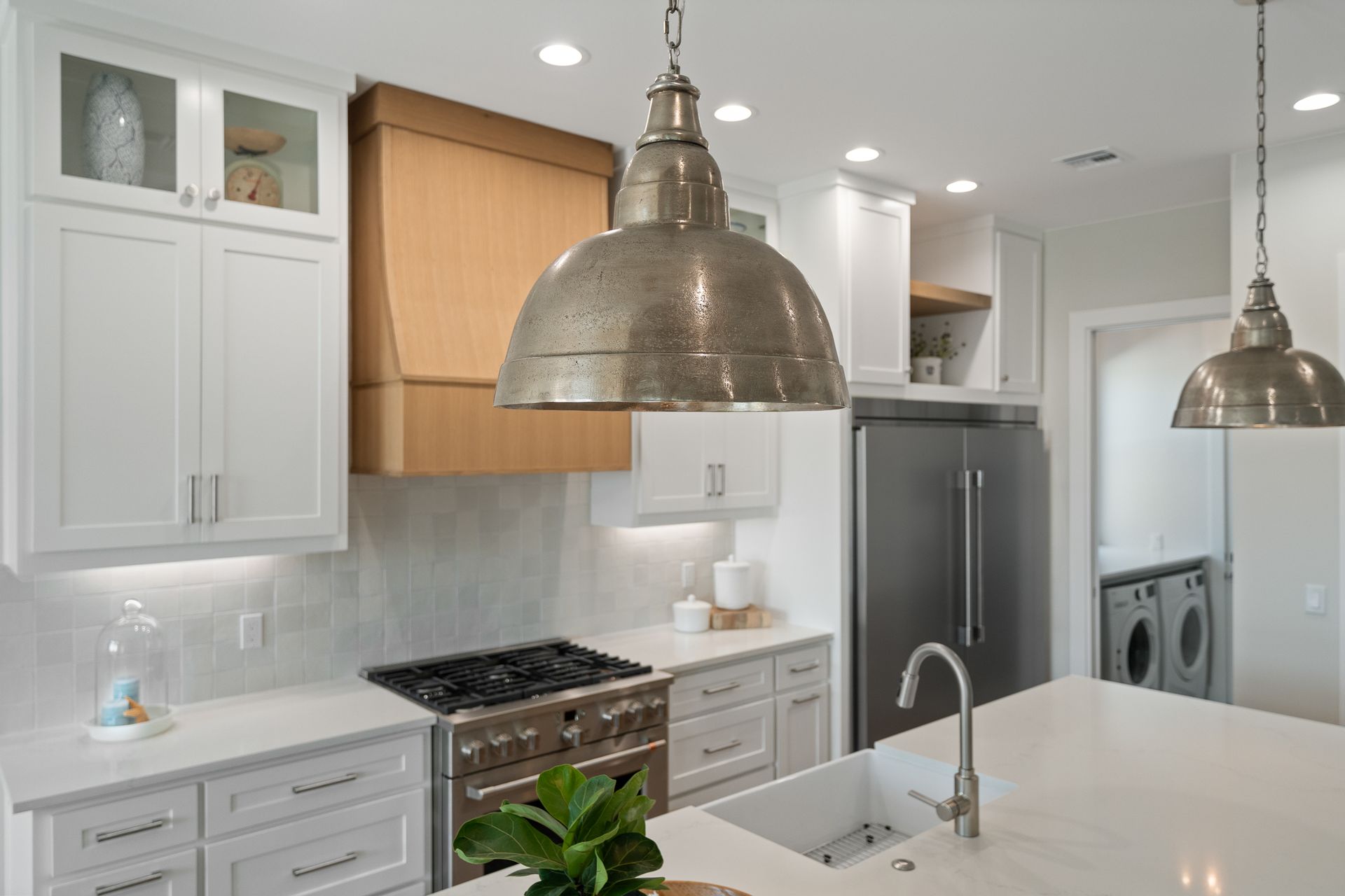 A kitchen with white cabinets , a stove , a refrigerator , and a sink.