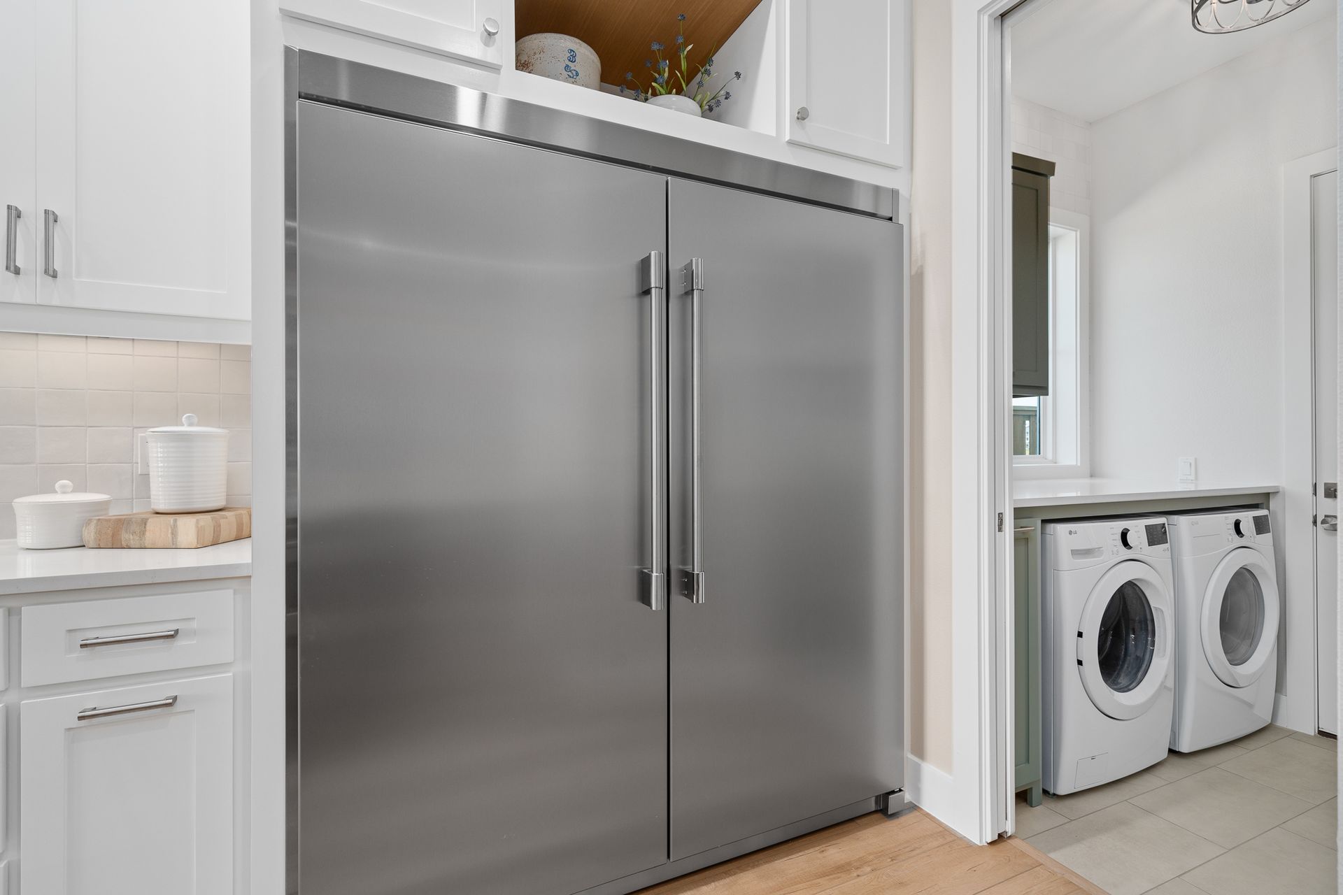 A stainless steel refrigerator is sitting in a laundry room next to a washer and dryer.
