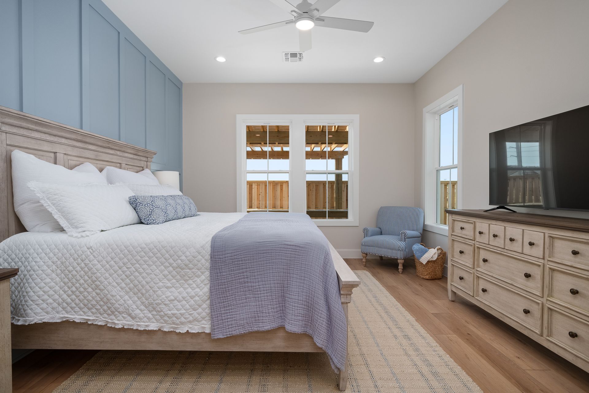 A bedroom with a king size bed , dresser , chair and television.