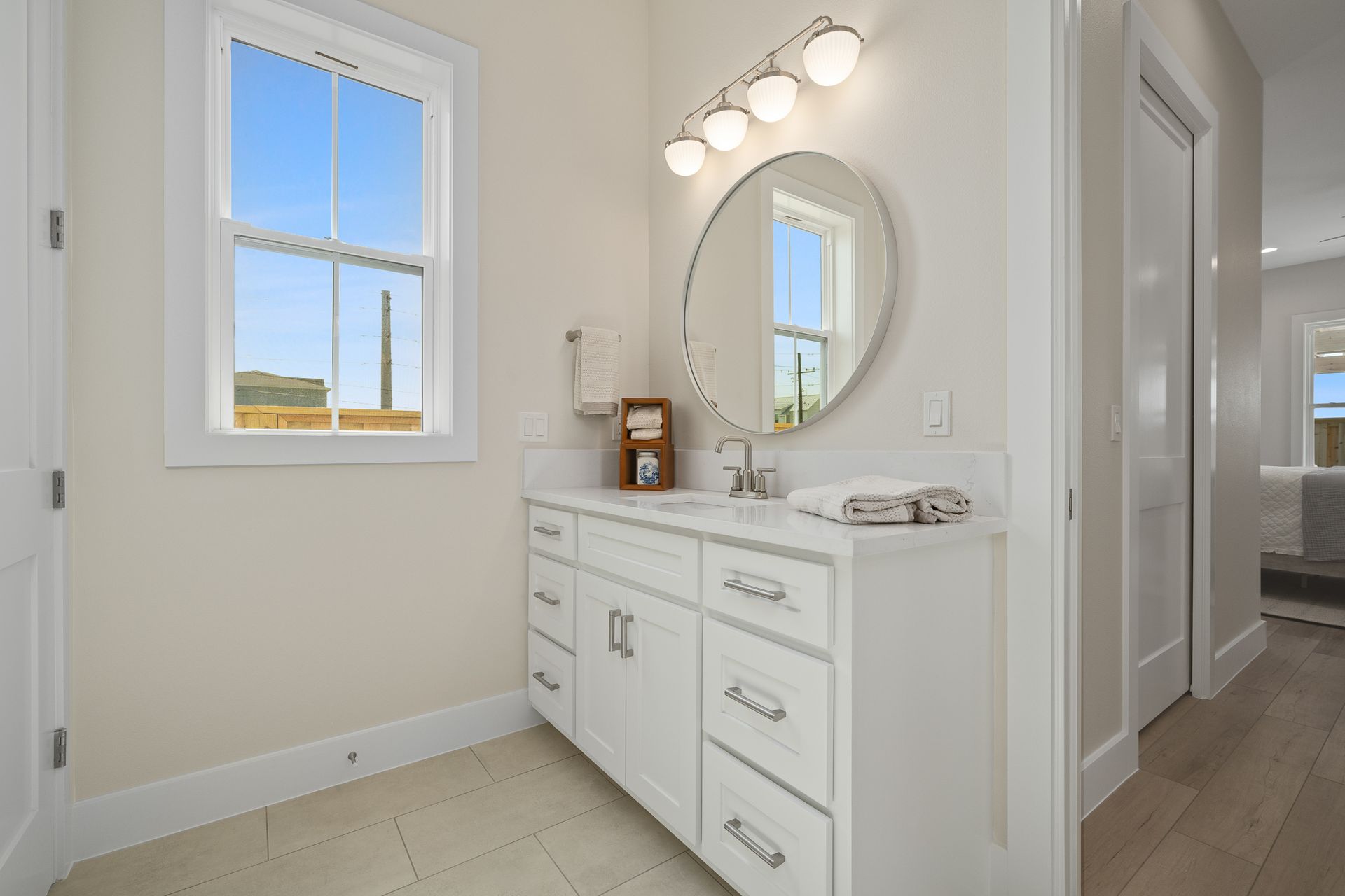 A bathroom with a sink , mirror and window.