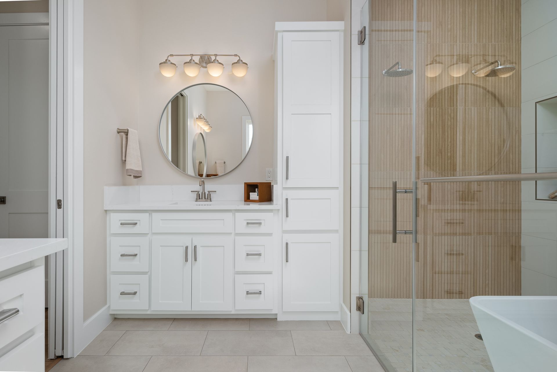 A bathroom with white cabinets and a round mirror