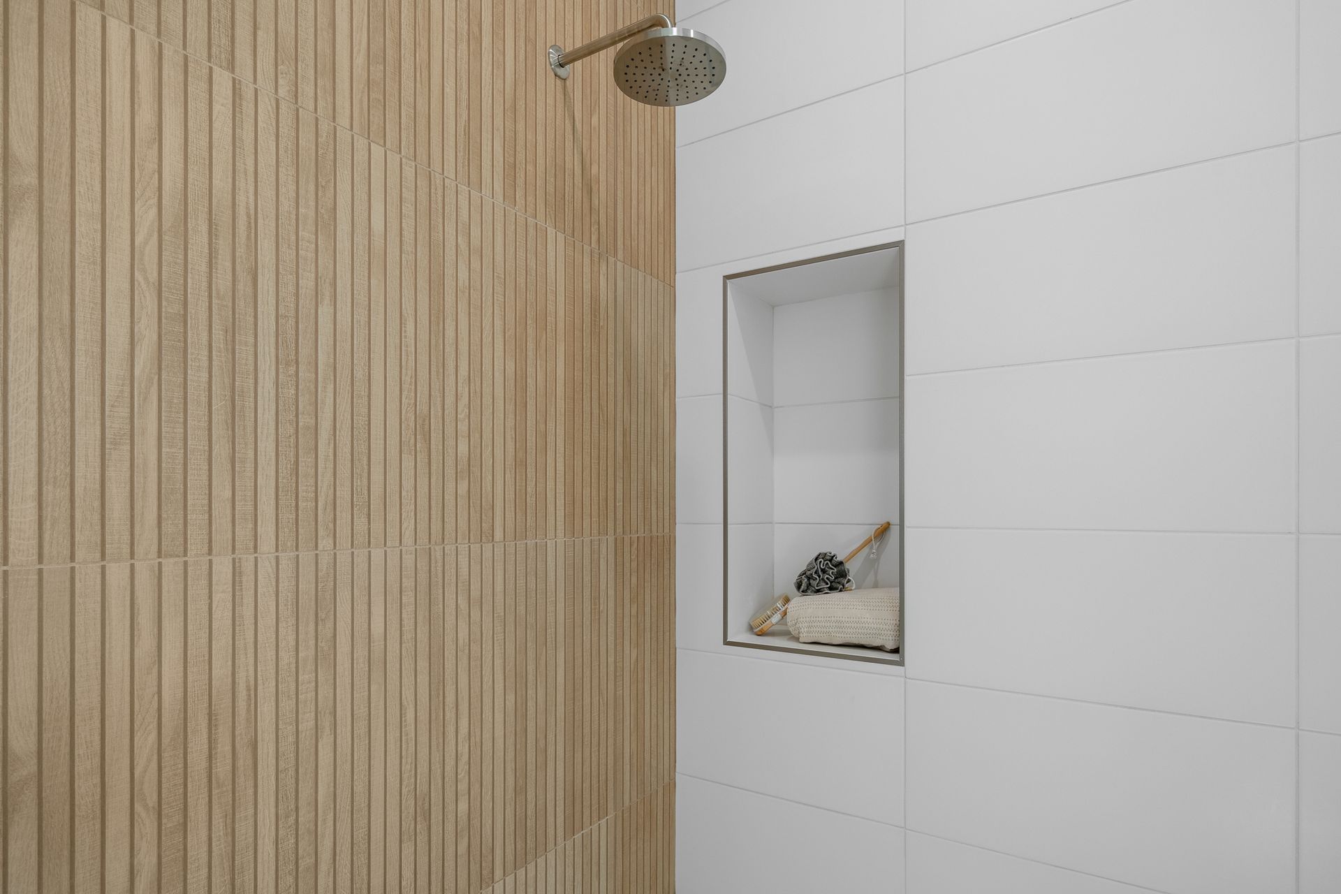 A shower with a wooden wall and a white tile wall.