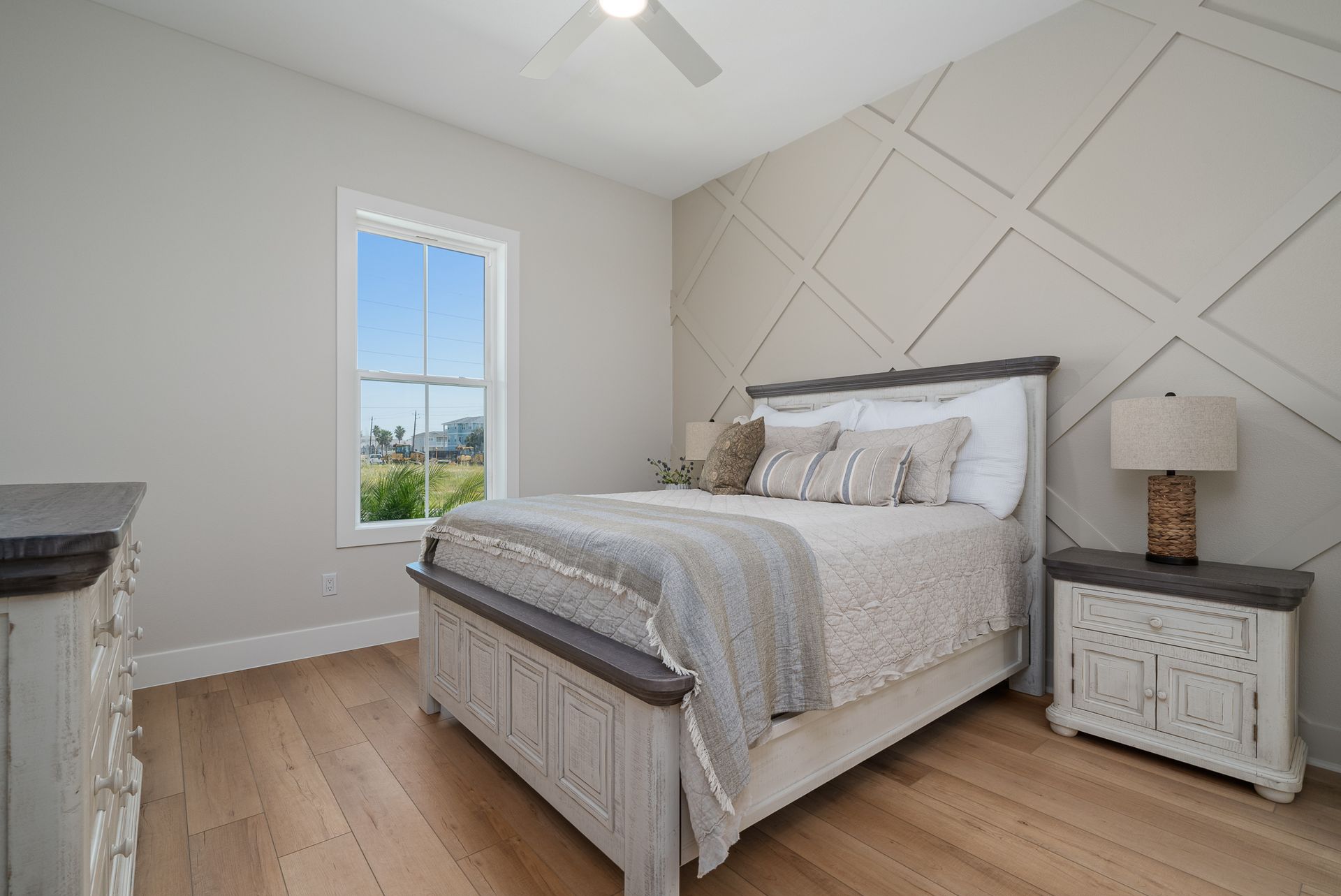 A bedroom with a bed , nightstand , dresser and window.
