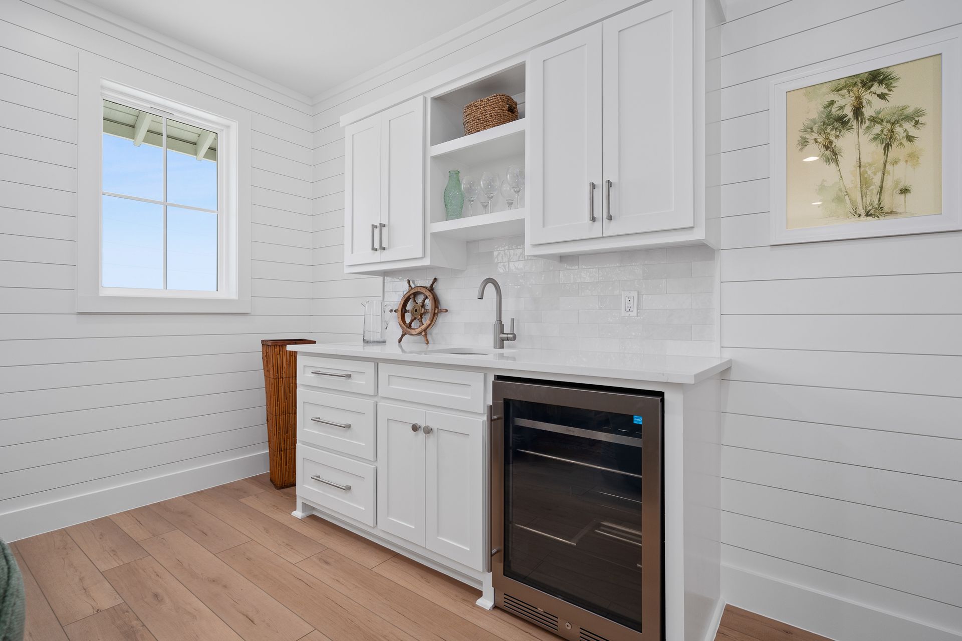 A kitchen with white cabinets , a sink , a refrigerator and a window.