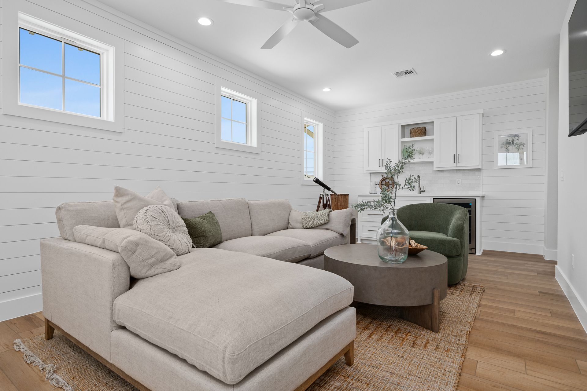 A living room with a couch , chair , coffee table and ceiling fan.