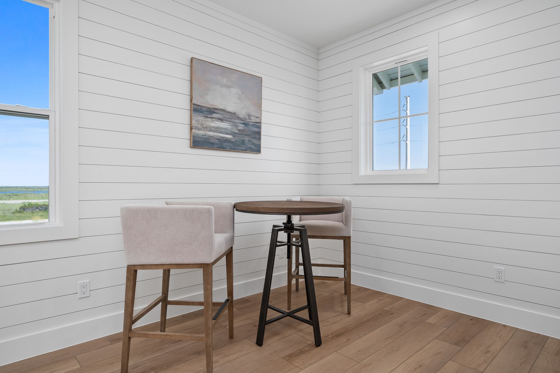 A room with a table and chairs and a painting on the wall.