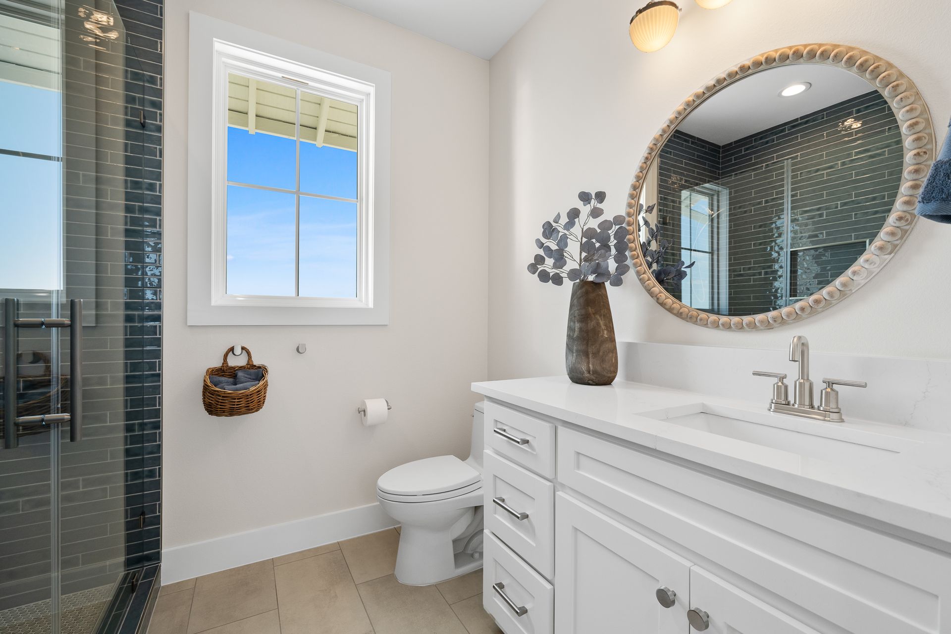 A bathroom with a toilet , sink , mirror and window.