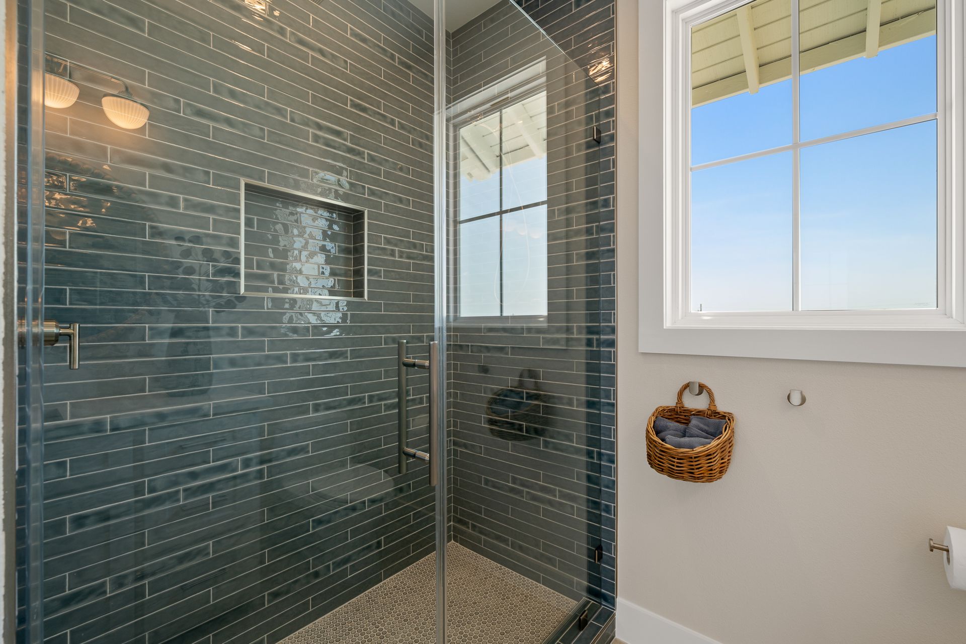 A bathroom with a walk in shower and a window.