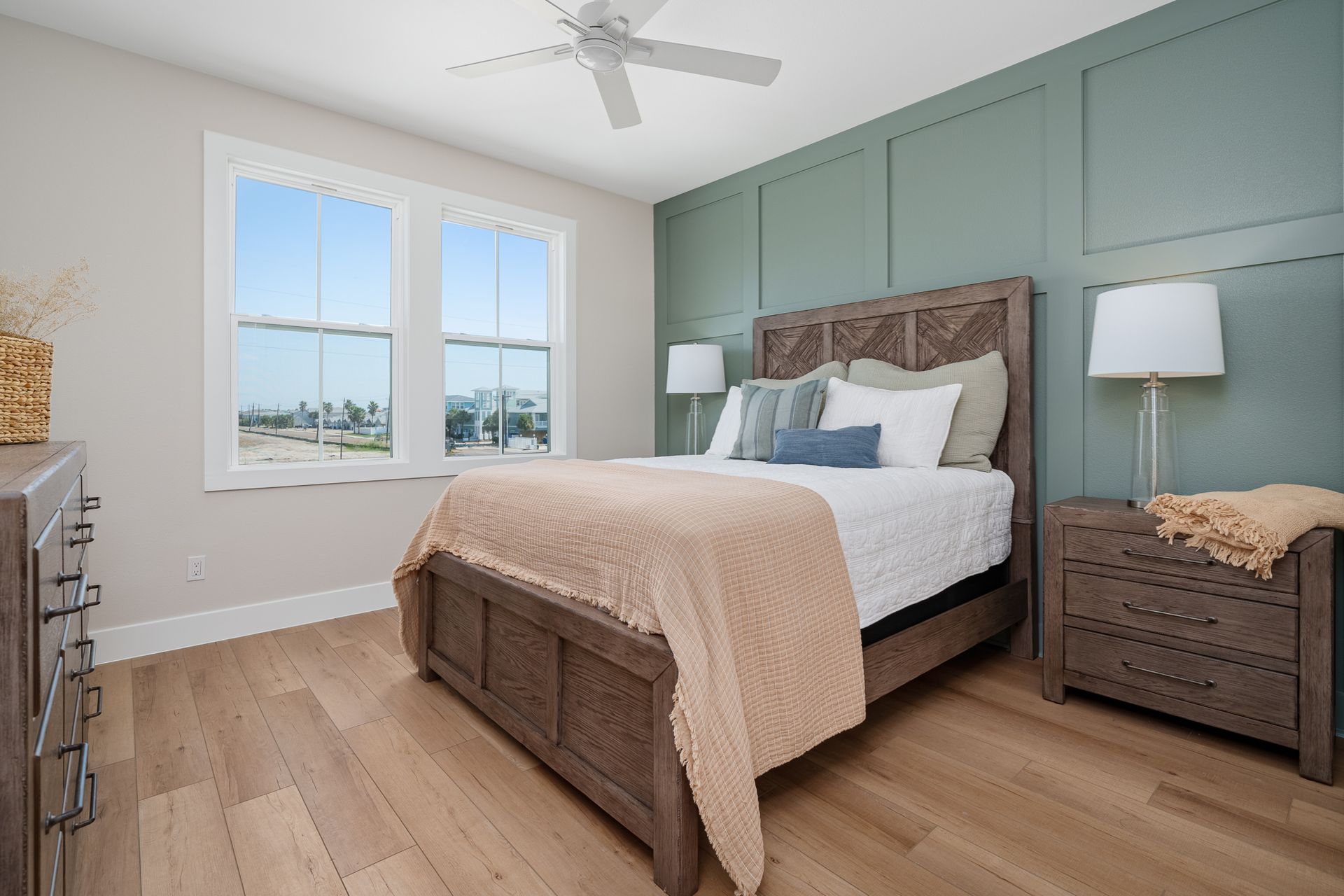 A bedroom with a bed , dresser , nightstand , and ceiling fan.
