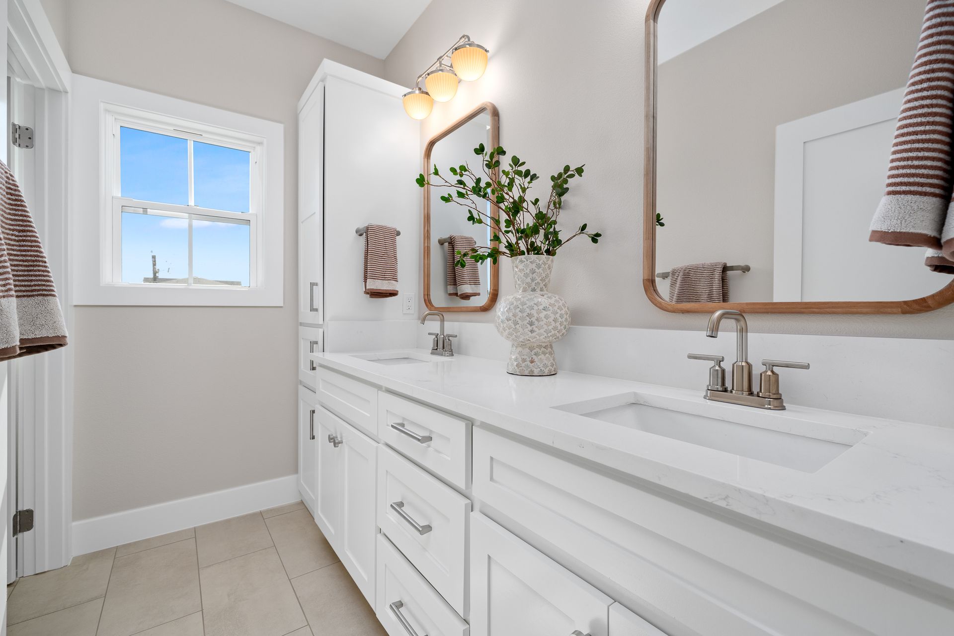 A bathroom with two sinks , a mirror and a window.