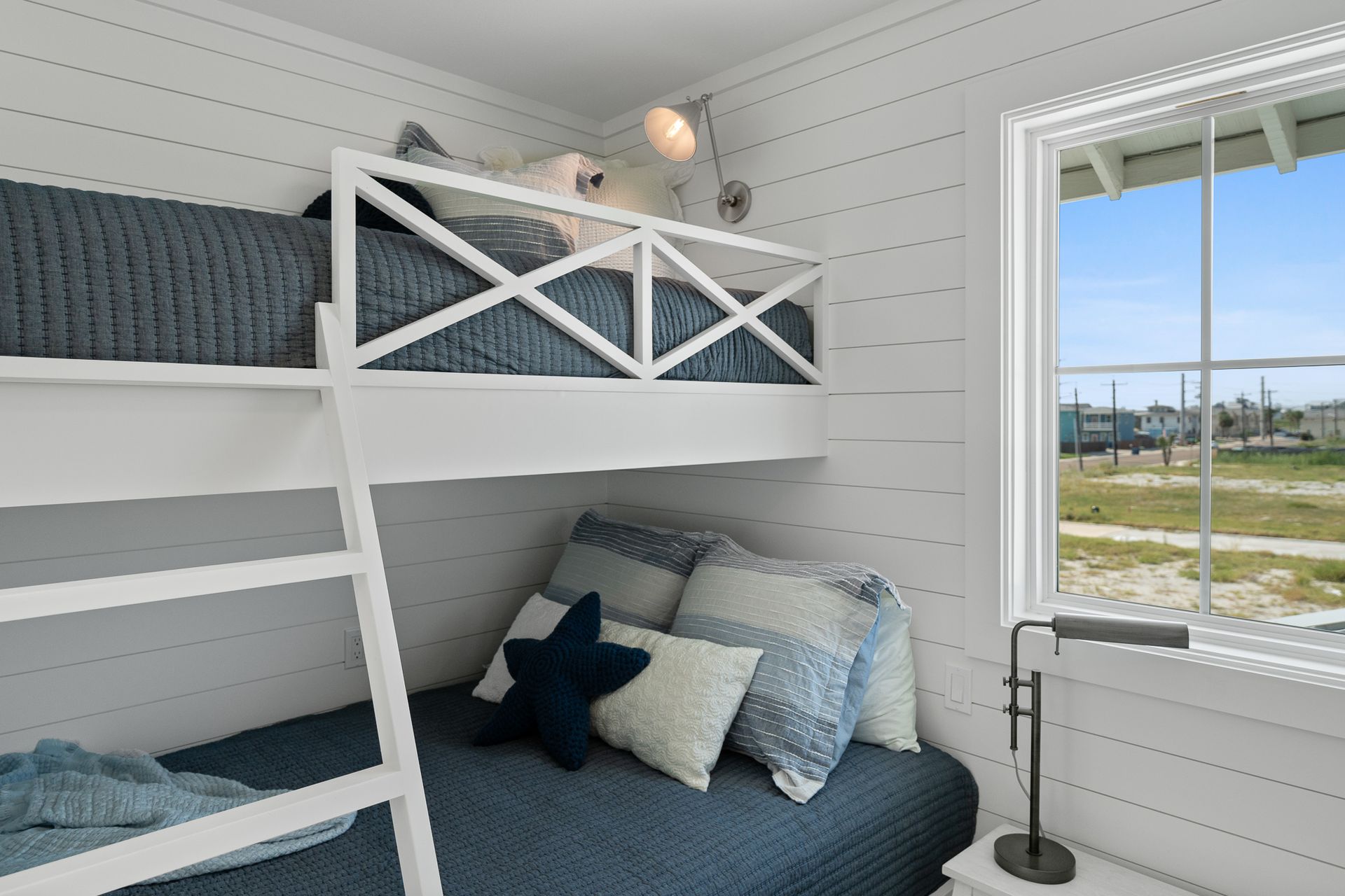 A bunk bed with a ladder in a bedroom next to a window.