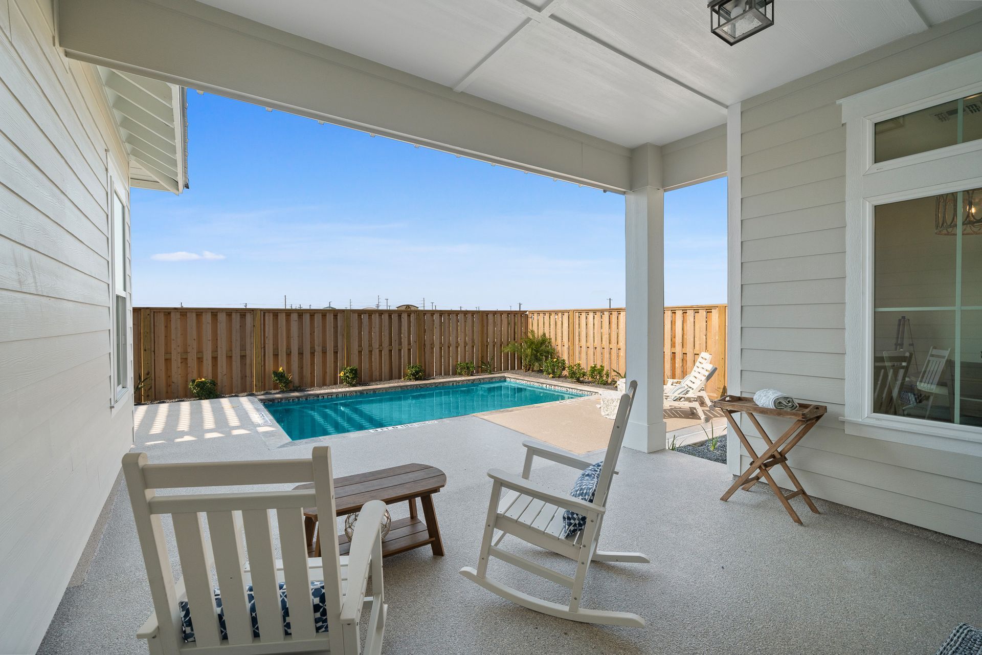 A patio with rocking chairs and a swimming pool in the background.