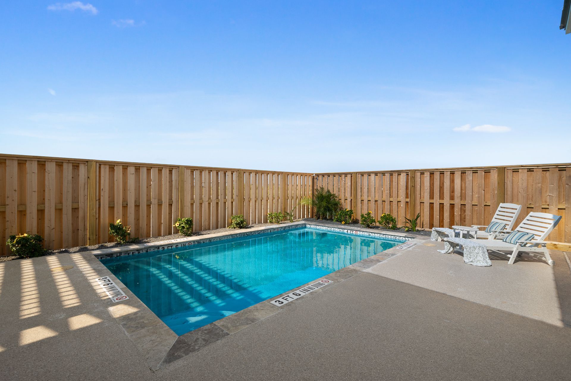 There is a large swimming pool in the backyard of a house.