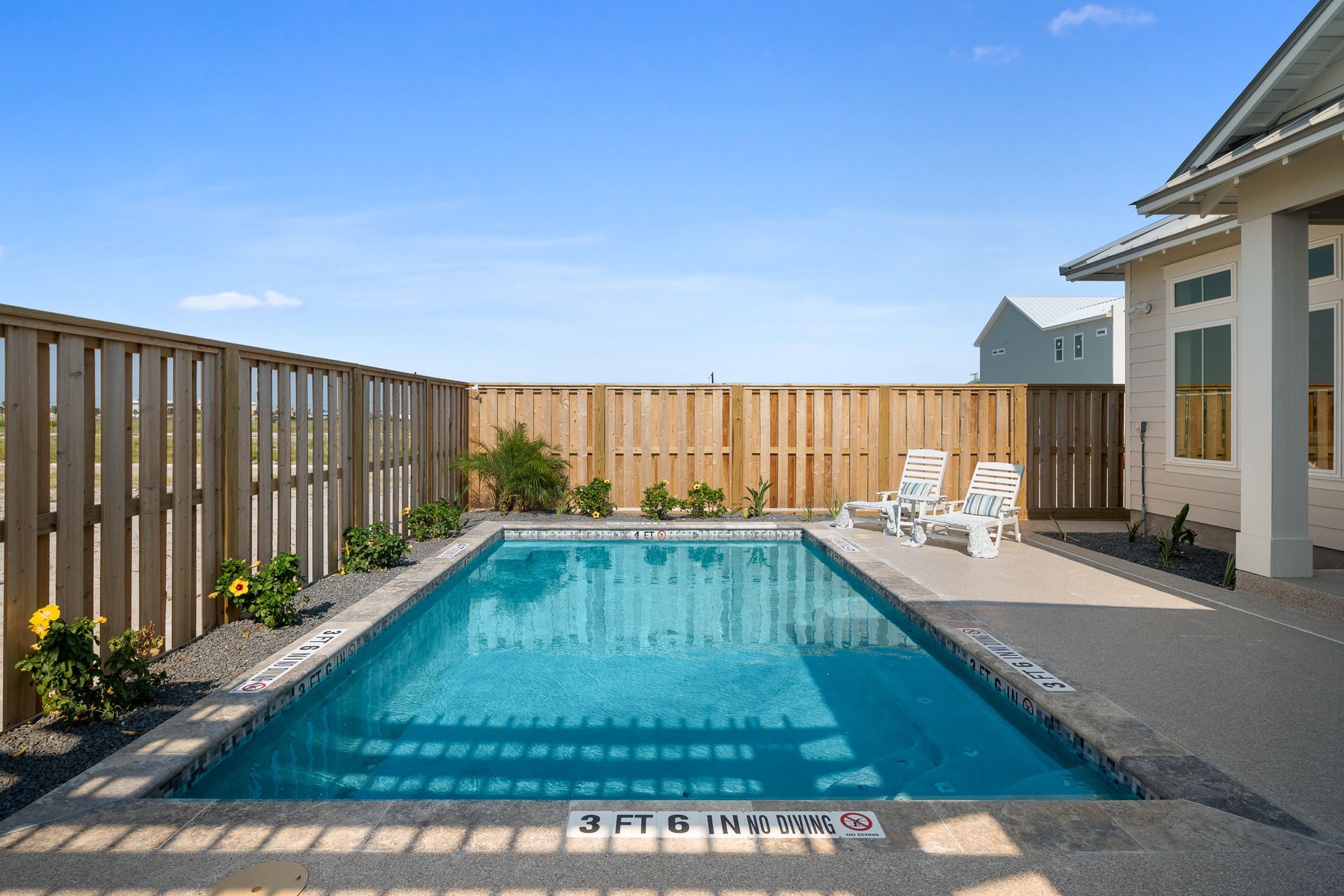 There is a large swimming pool in the backyard of a house.