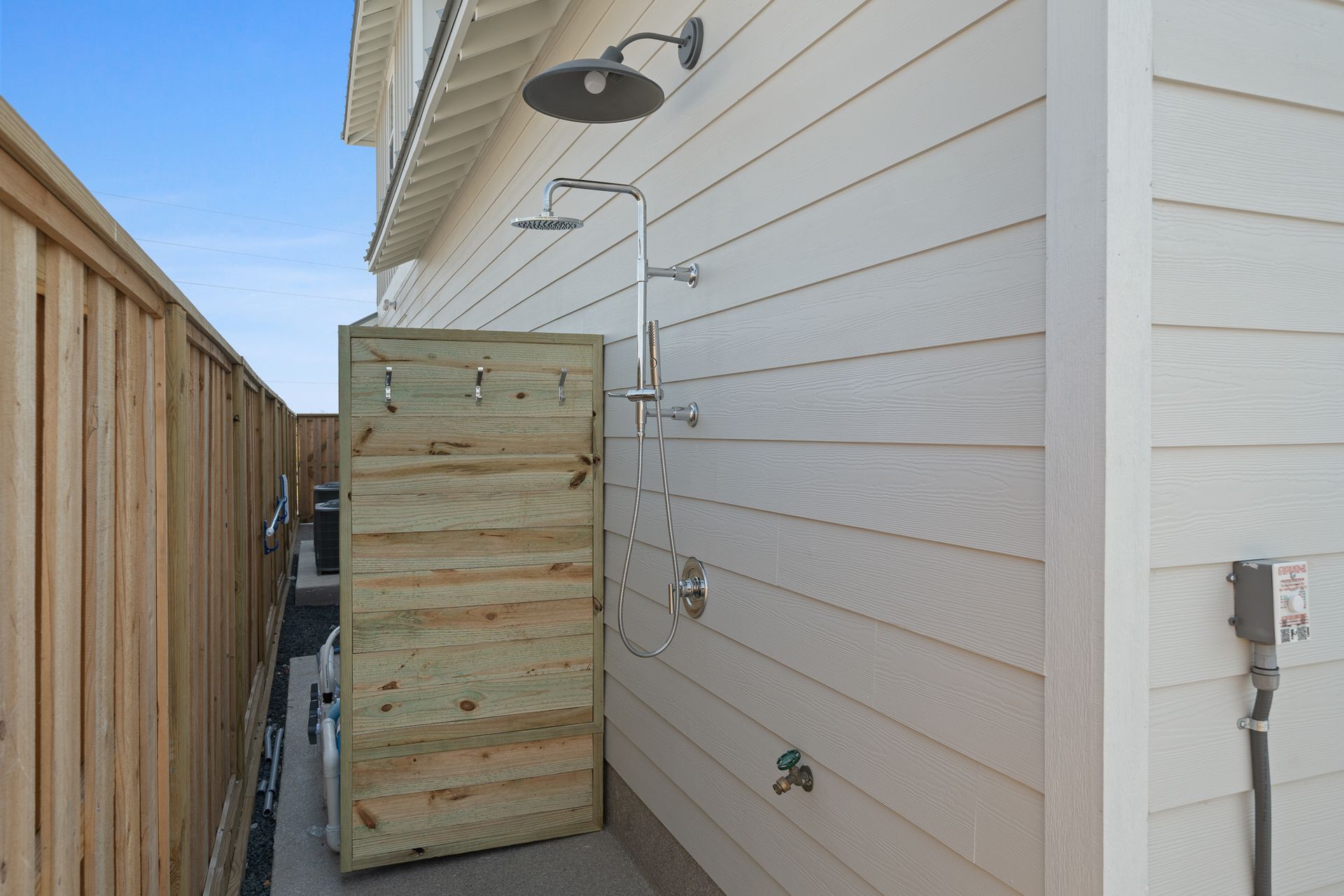 A house with a wooden fence and a shower on the side of it.