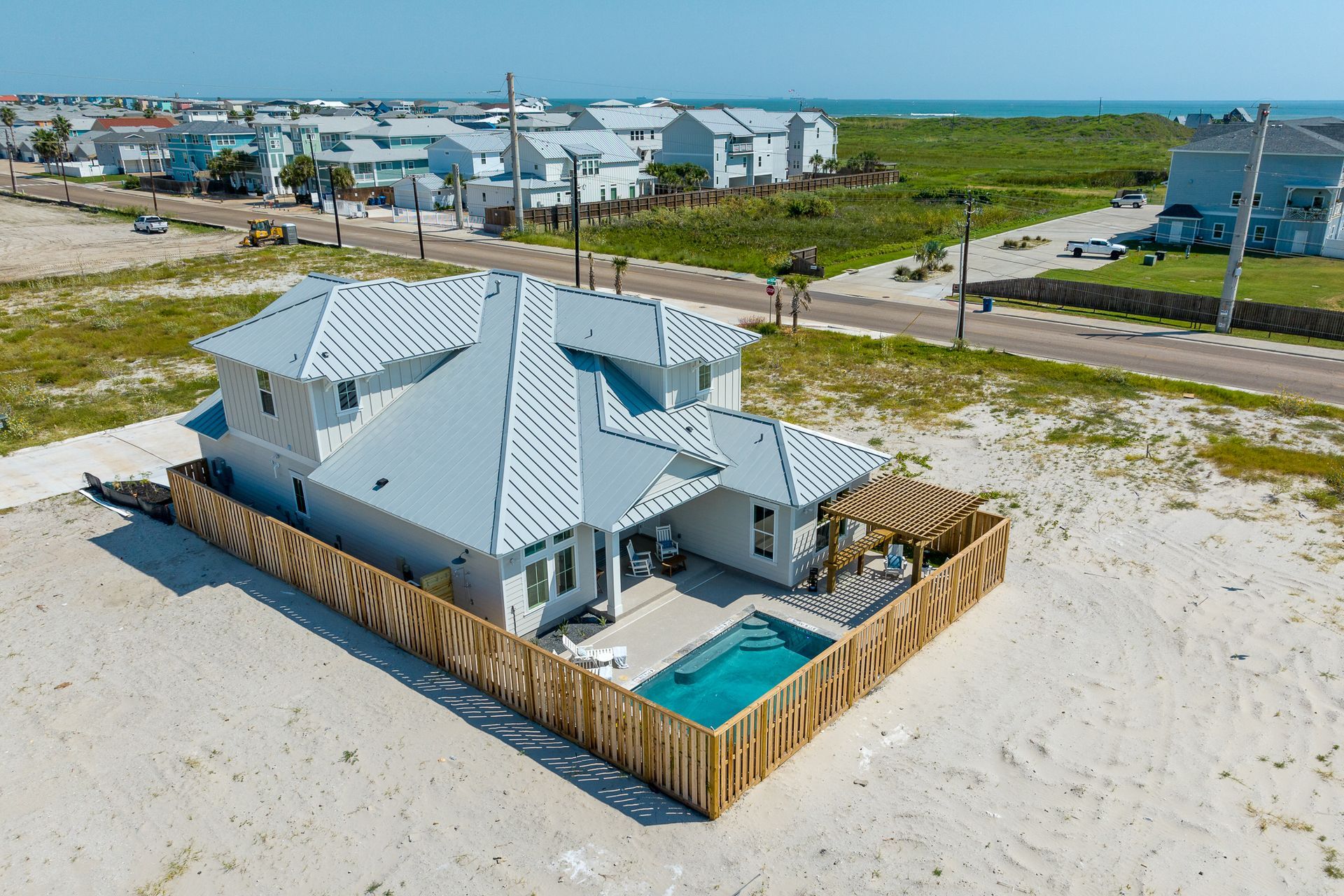 An aerial view of a house with a pool on the beach.