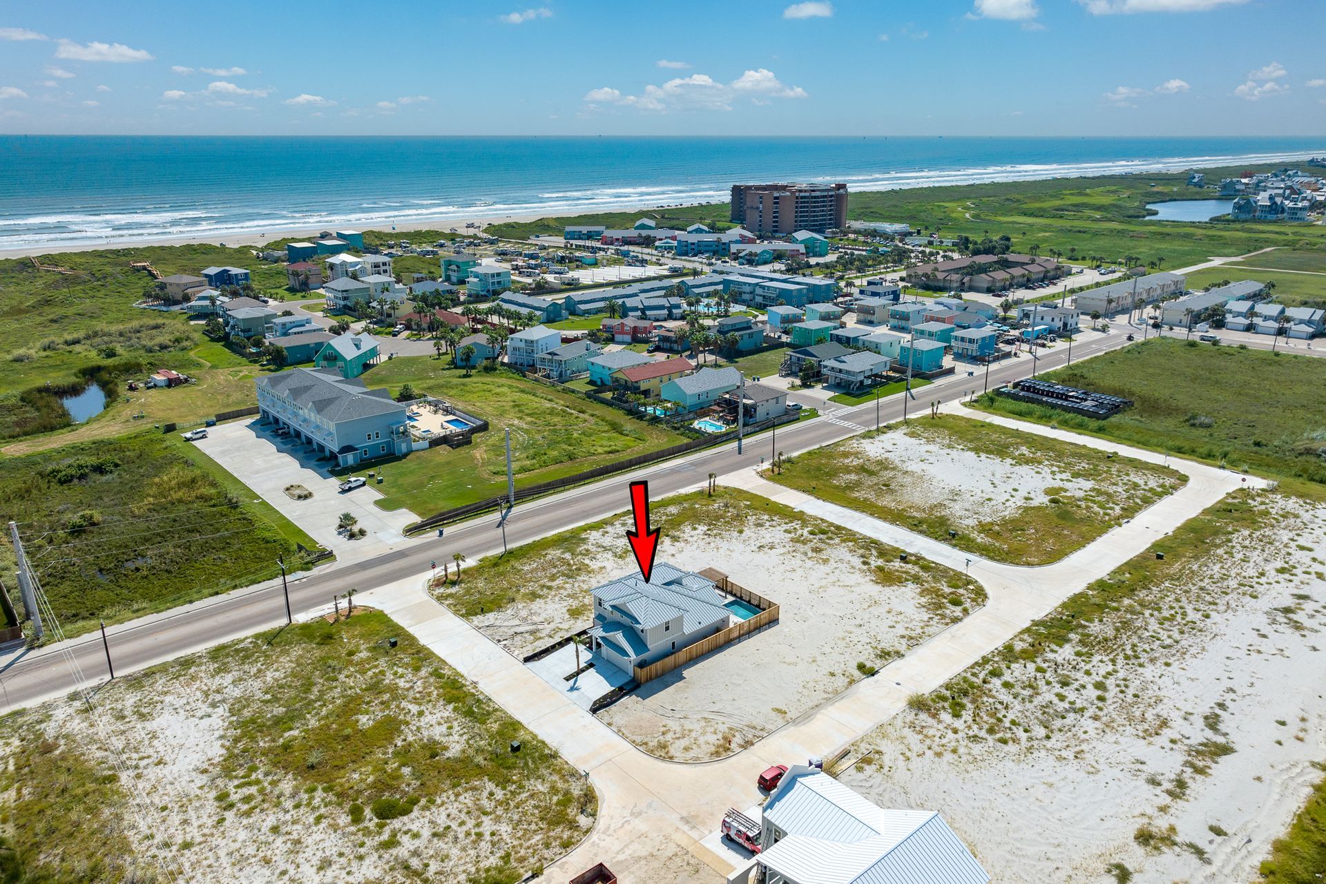 An aerial view of a house on the beach with a red arrow pointing to it