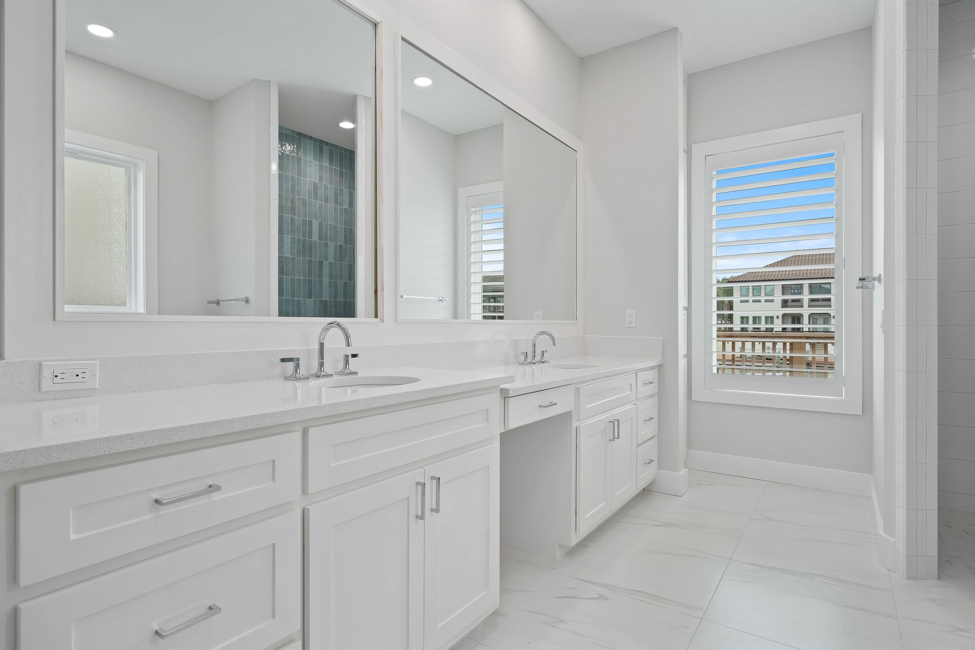 A bathroom with two sinks , two mirrors and a window.