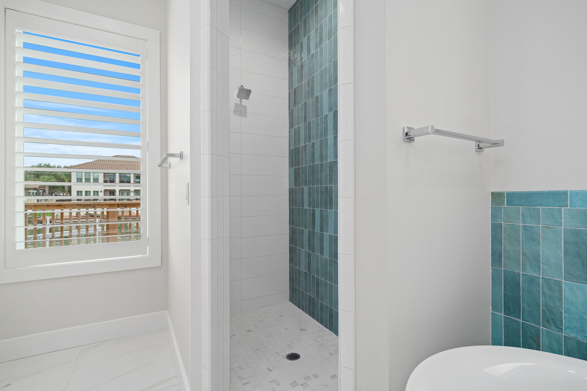 A bathroom with a walk in shower and a window.