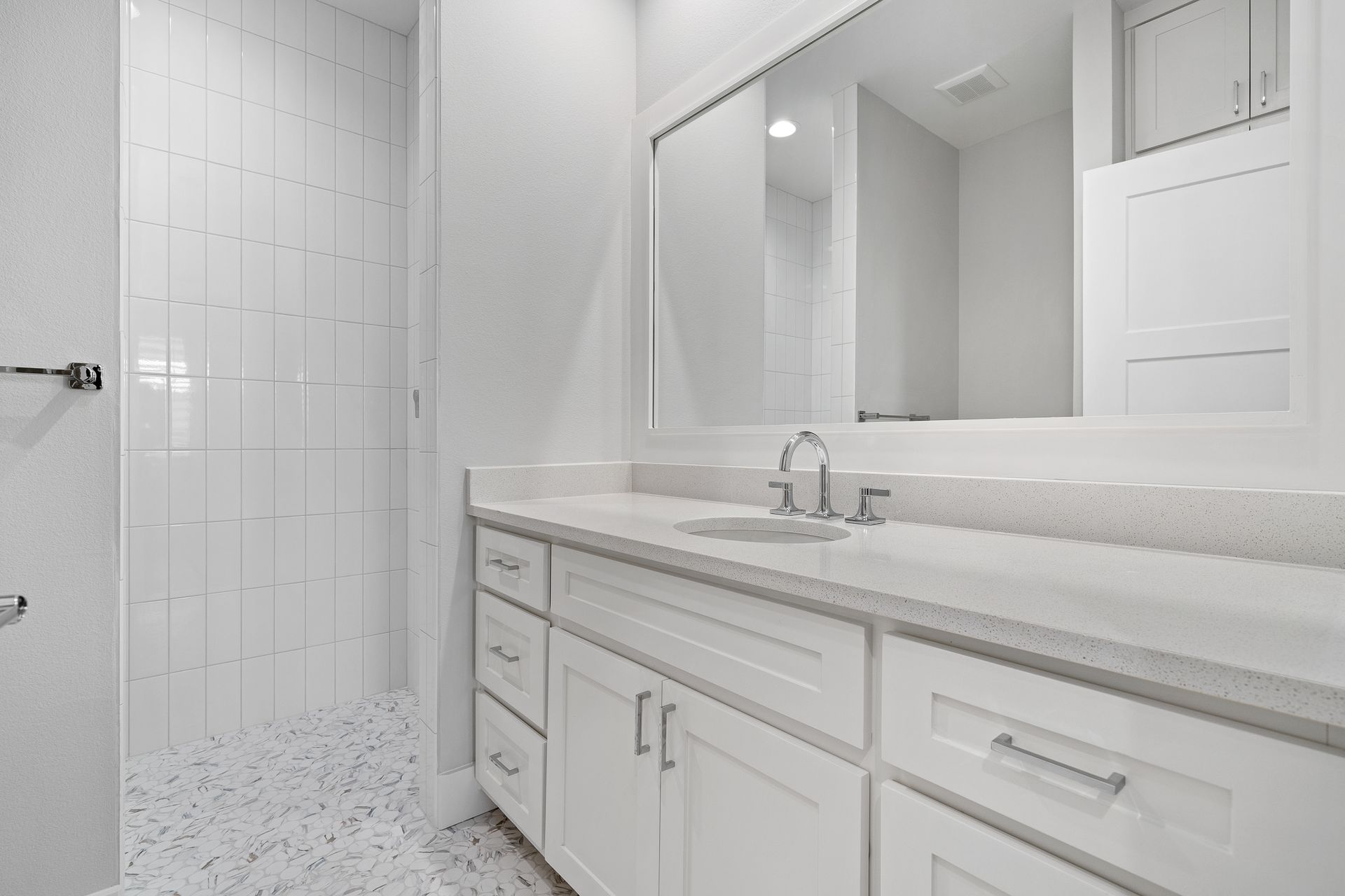 A bathroom with a sink , mirror and walk in shower.