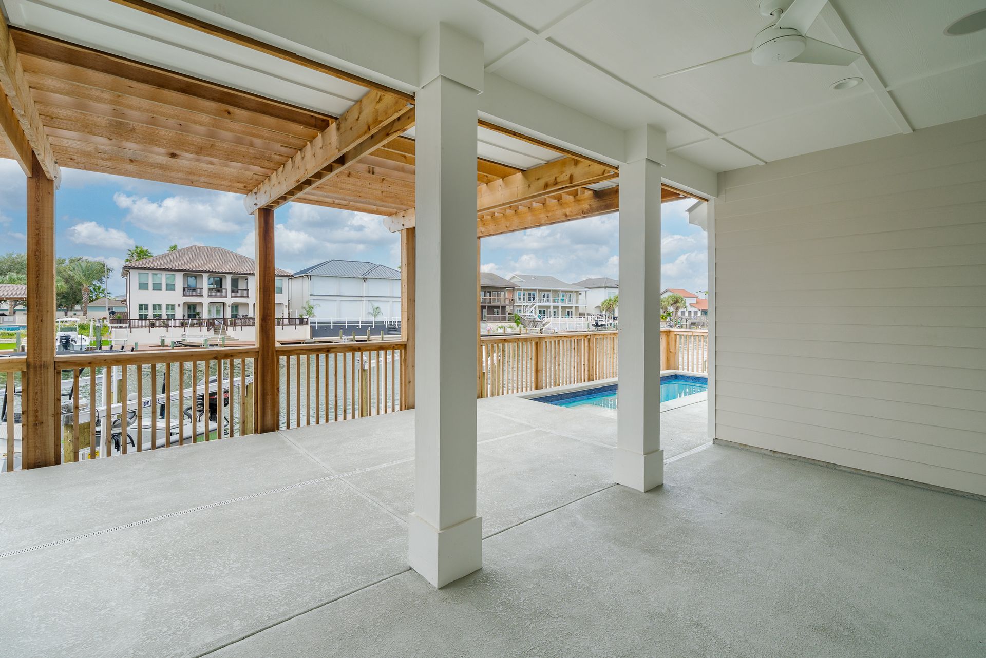 An empty patio with a ceiling fan and a view of a pool.