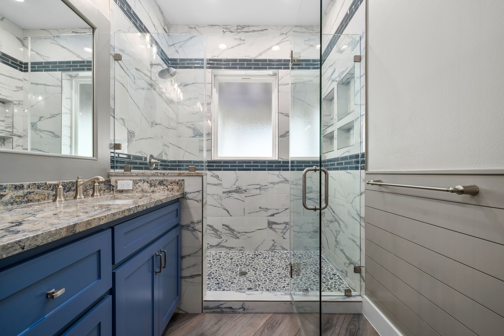 Blue vanity bathroom with marble and glass shower.