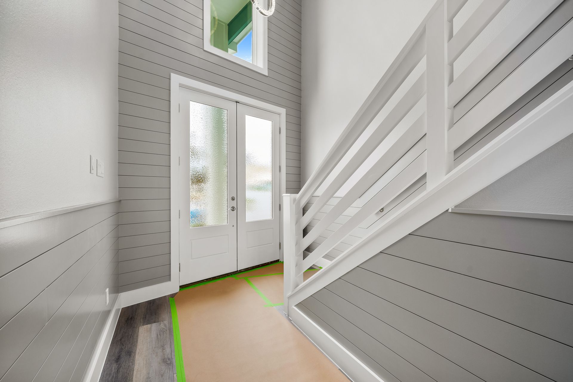 Hallway with white railing, gray shiplap walls, and double doors.