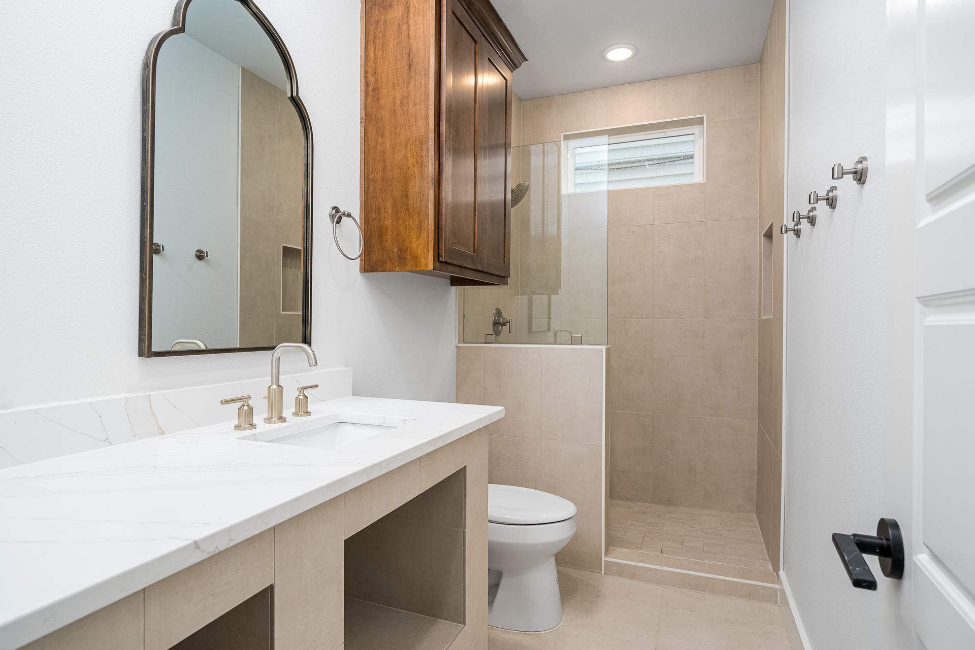 A bathroom with a toilet , sink , mirror and walk in shower.