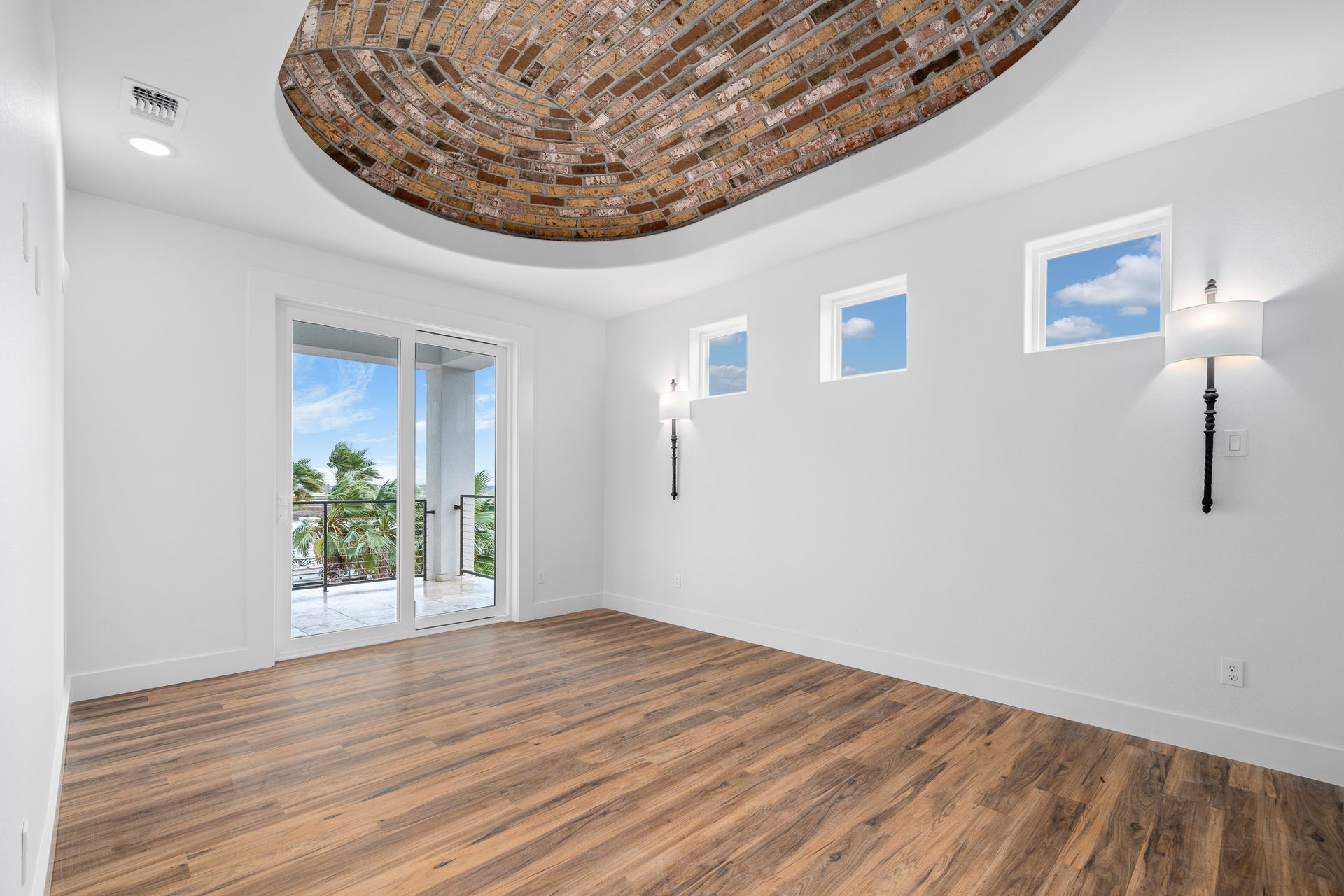 An empty room with hardwood floors and a balcony.