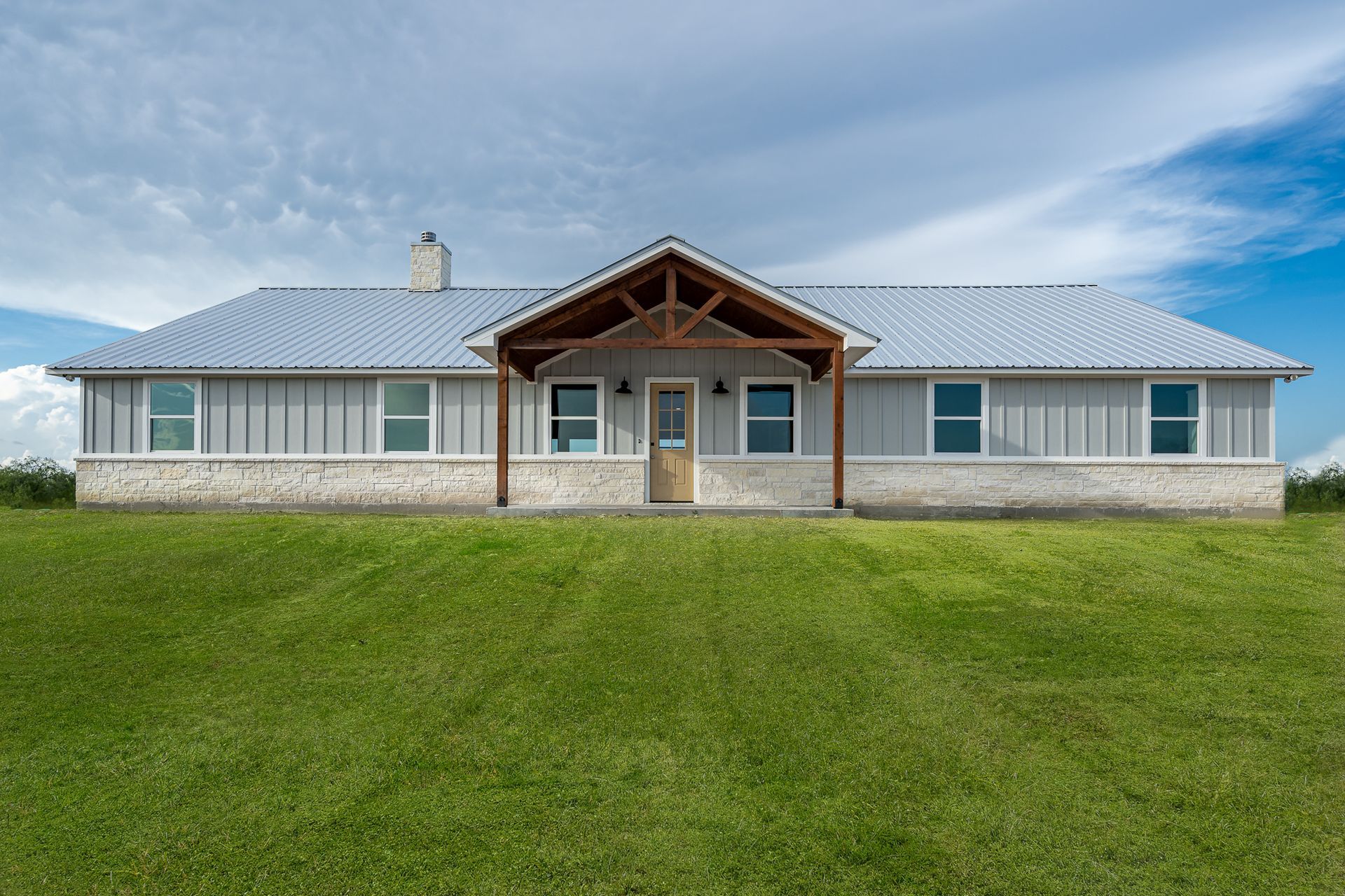 A large house is sitting on top of a lush green field.