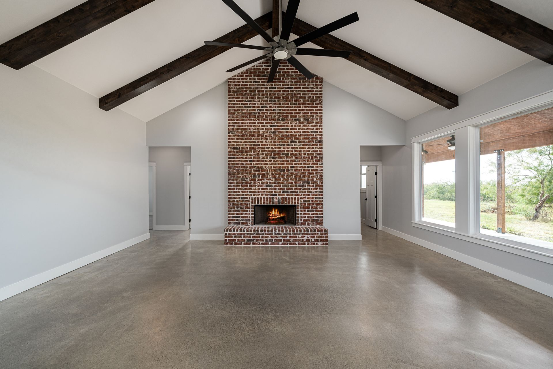 An empty living room with a brick fireplace and ceiling fan
