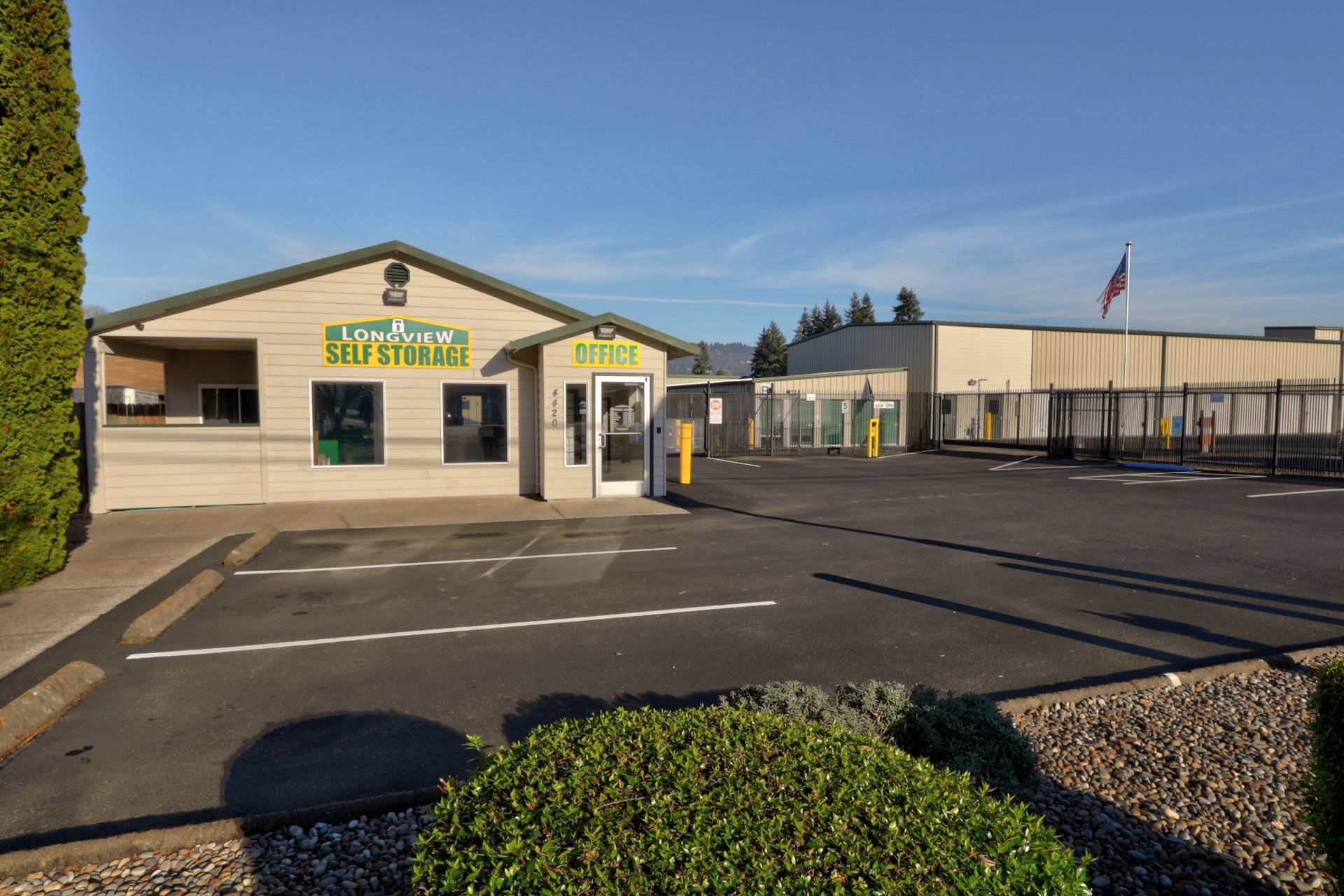 Storage facility with beige office building; blue sky; parking lot.