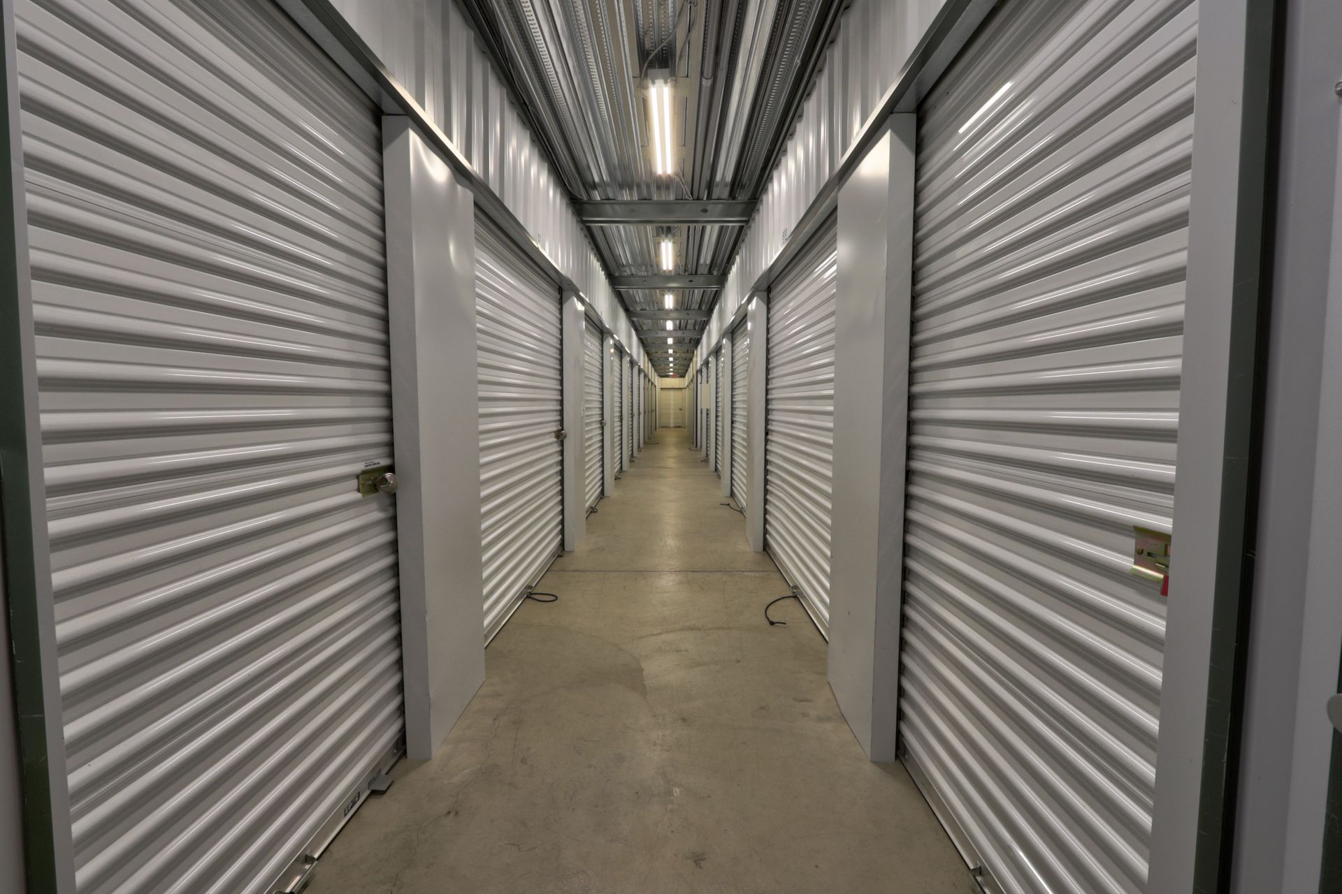 Hallway of storage units with closed, ribbed metal doors.