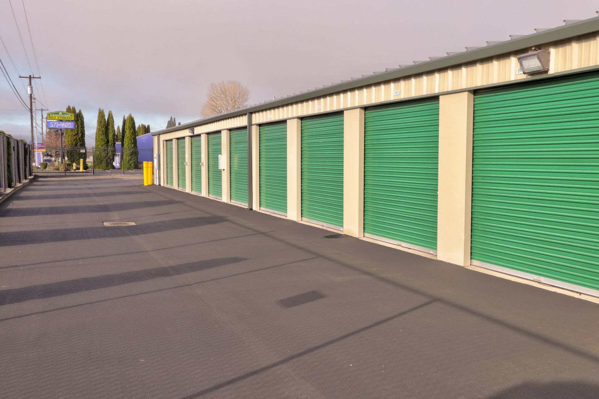 Storage units with green doors and a paved driveway.