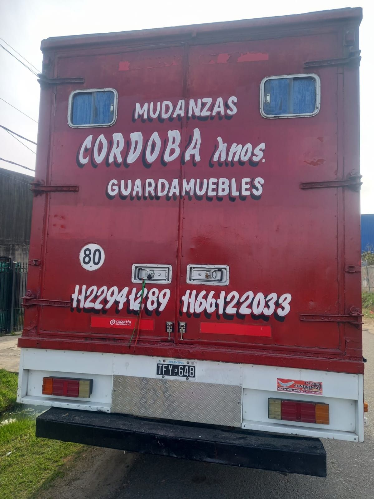 Camión de mudanzas rojo con la leyenda 