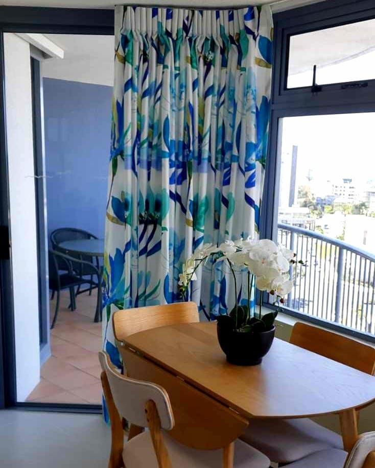 A Dining Room Table With a Vase of Flowers on It — Artizen Curtains in Mooloolaba, QLD