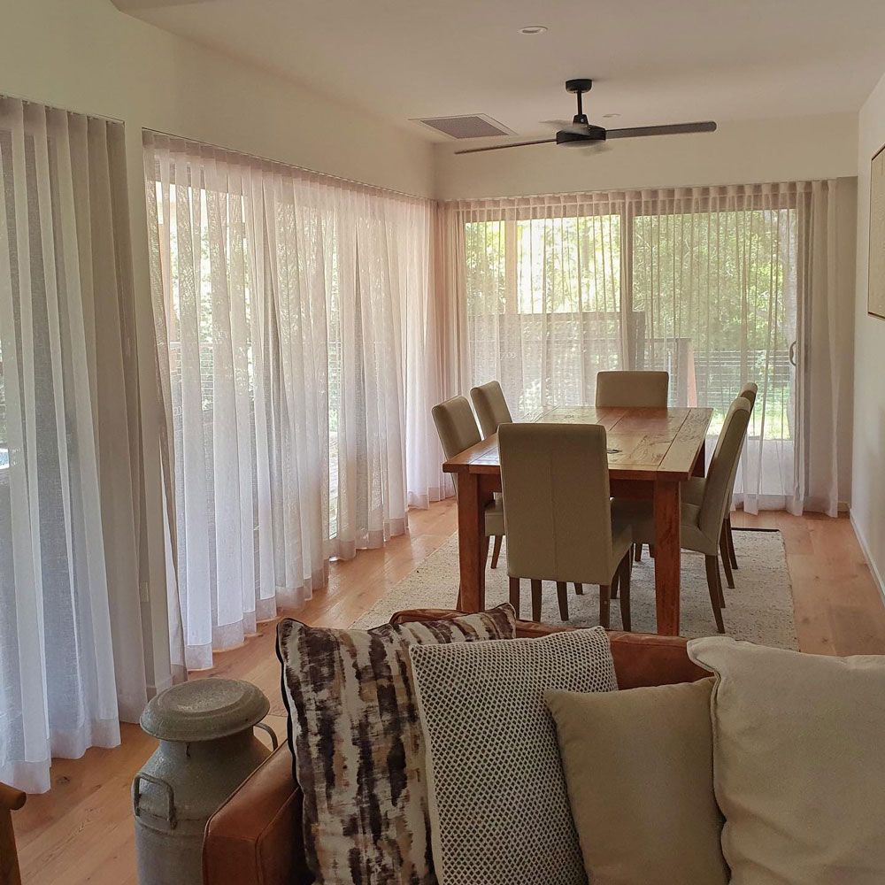 A Living Room with A Table and Chairs and A Ceiling Fan — Artizen Curtains in Palmwoods, QLD