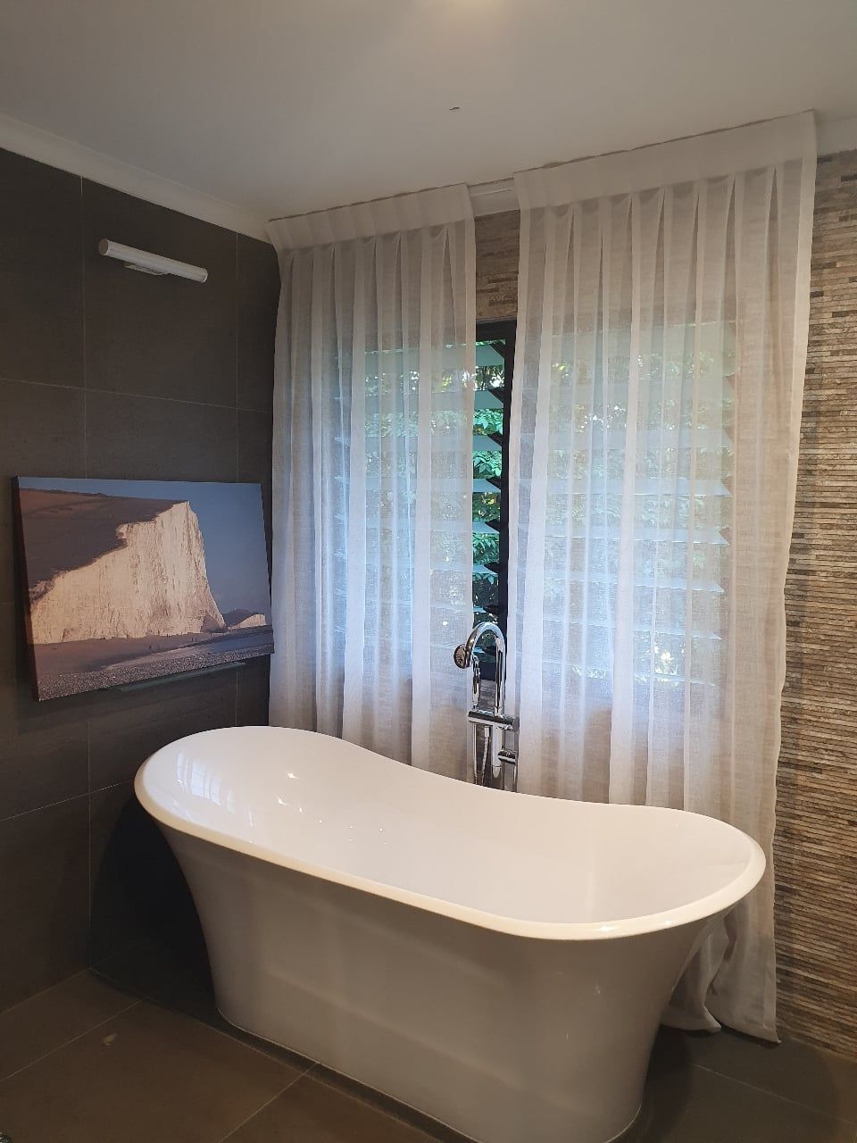 A Bathroom With a Bathtub and a Painting on the Wall — Artizen Curtains in Mooloolaba, QLD