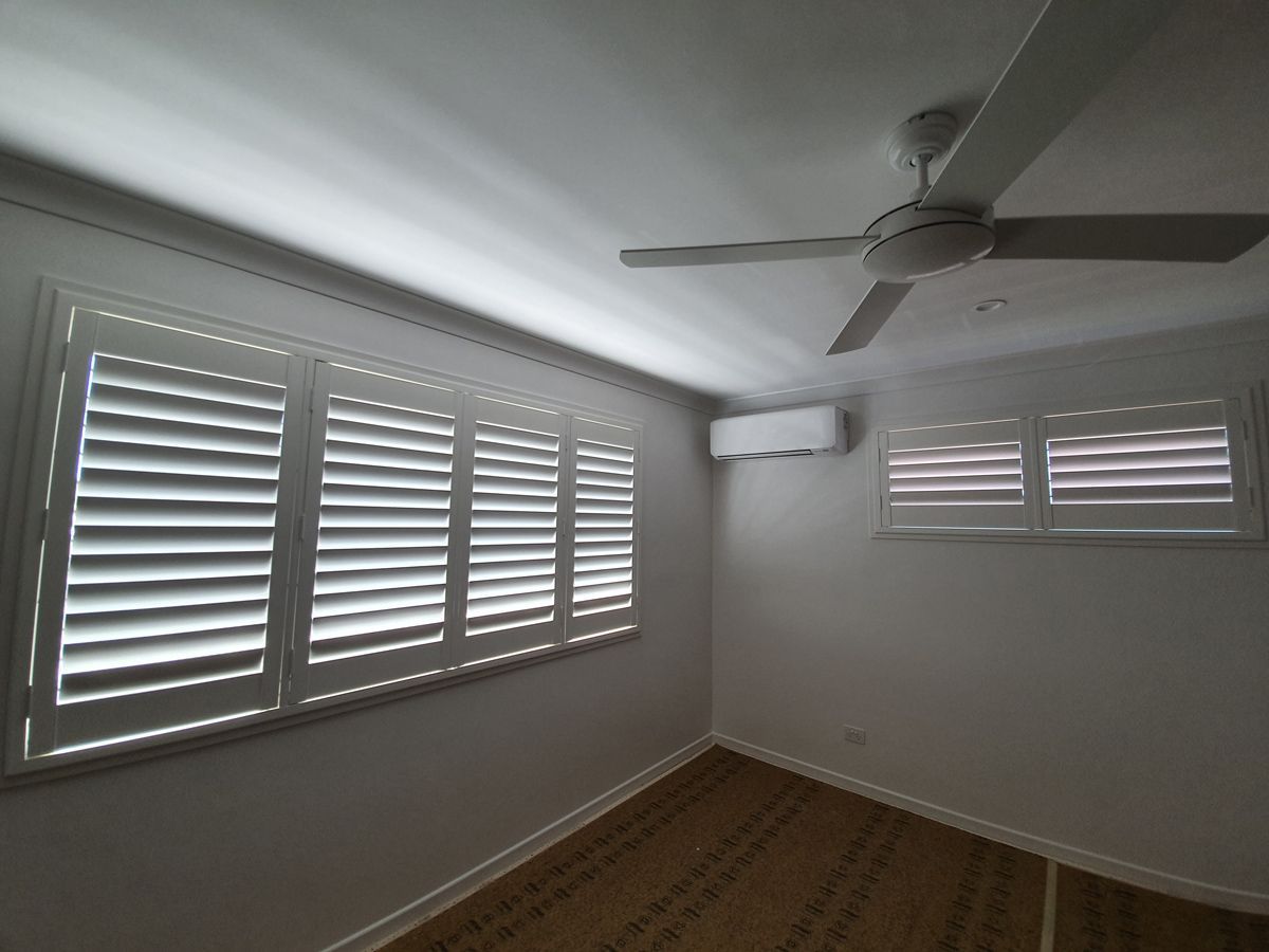 A Bedroom With White Shutters and a Ceiling Fan — Artizen Curtains in Mooloolaba, QLD