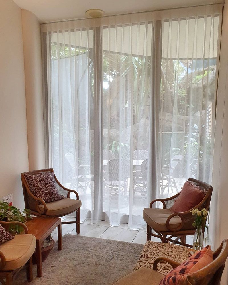 A Living Room with Two Chairs and A Table in Front of A Large Window — Artizen Curtains in Noosa, QLD