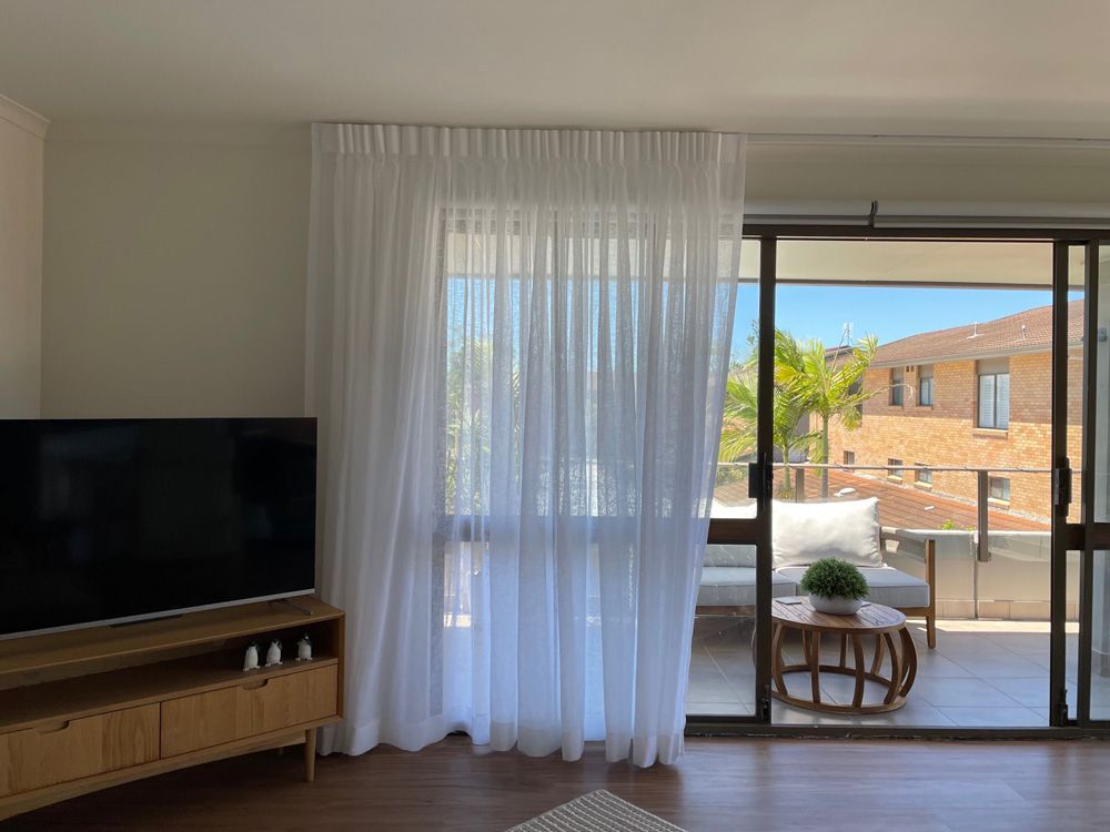 A Living Room With a Flat Screen TV and a Sliding Glass Door — Artizen Curtains in Mooloolaba, QLD
